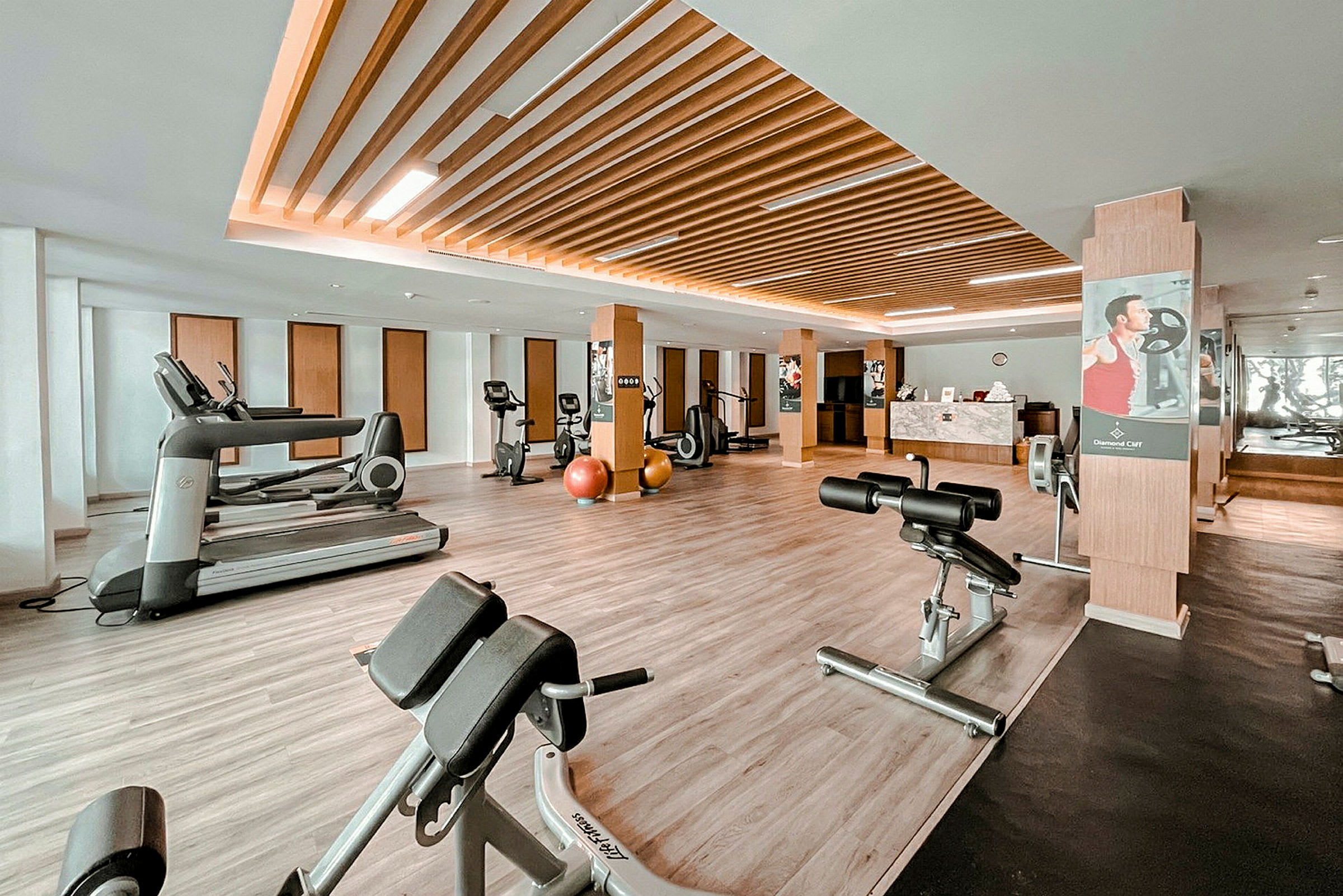 Ett modernt gym med träningsmaskiner och utrustning på ett stilrent trägolv. (AI-genererad text)
