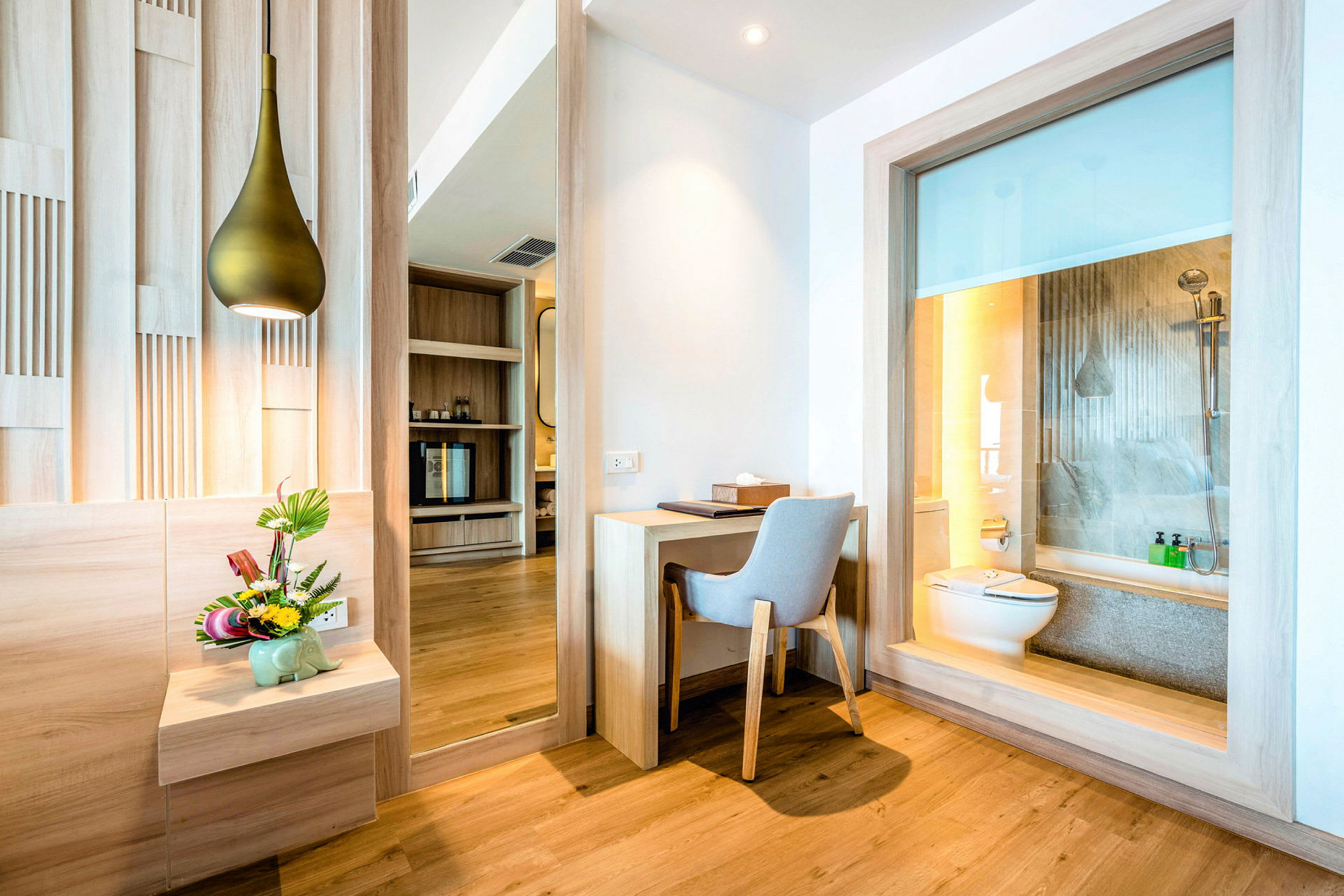 Ett hotellrum med skrivbord, stol, blomdekoration och öppning mot badrum. (AI-genererad text)