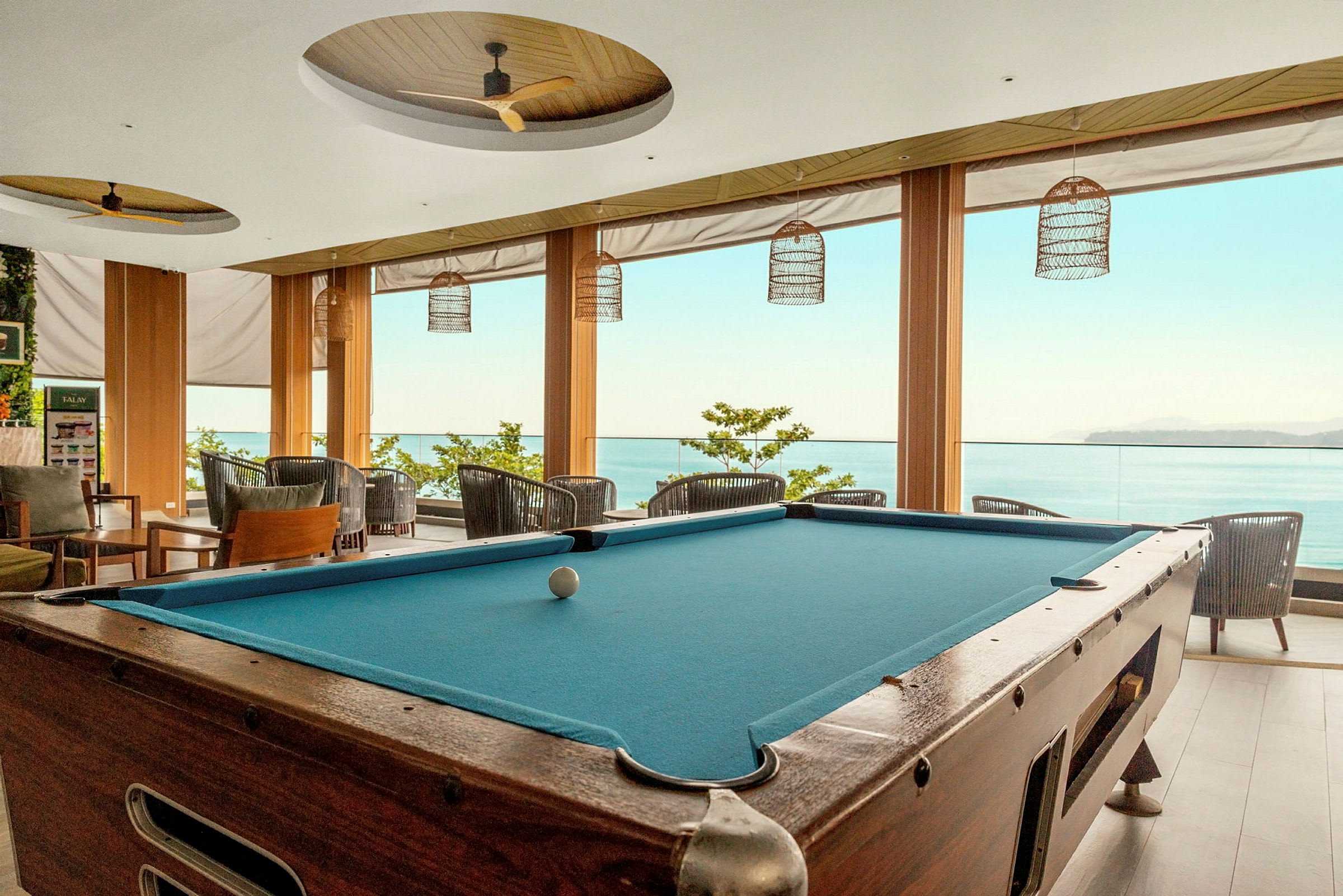 Biljardbord i en ljus lounge med utsikt mot havet. (AI-genererad text)