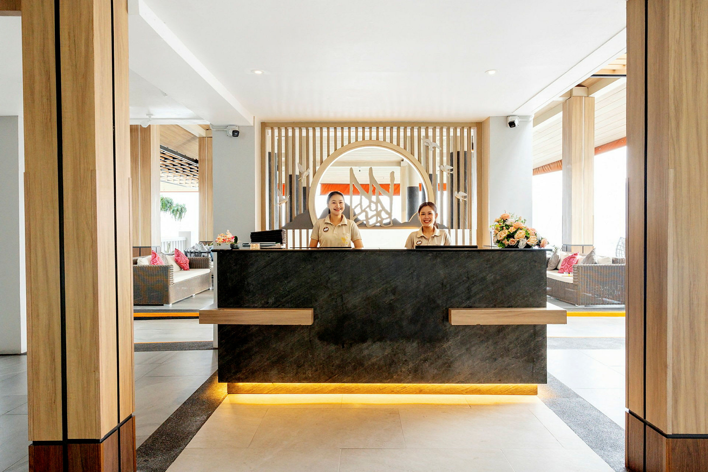 Receptionen i en hotellobby med moderna trädetaljer och blommor. (AI-genererad text)