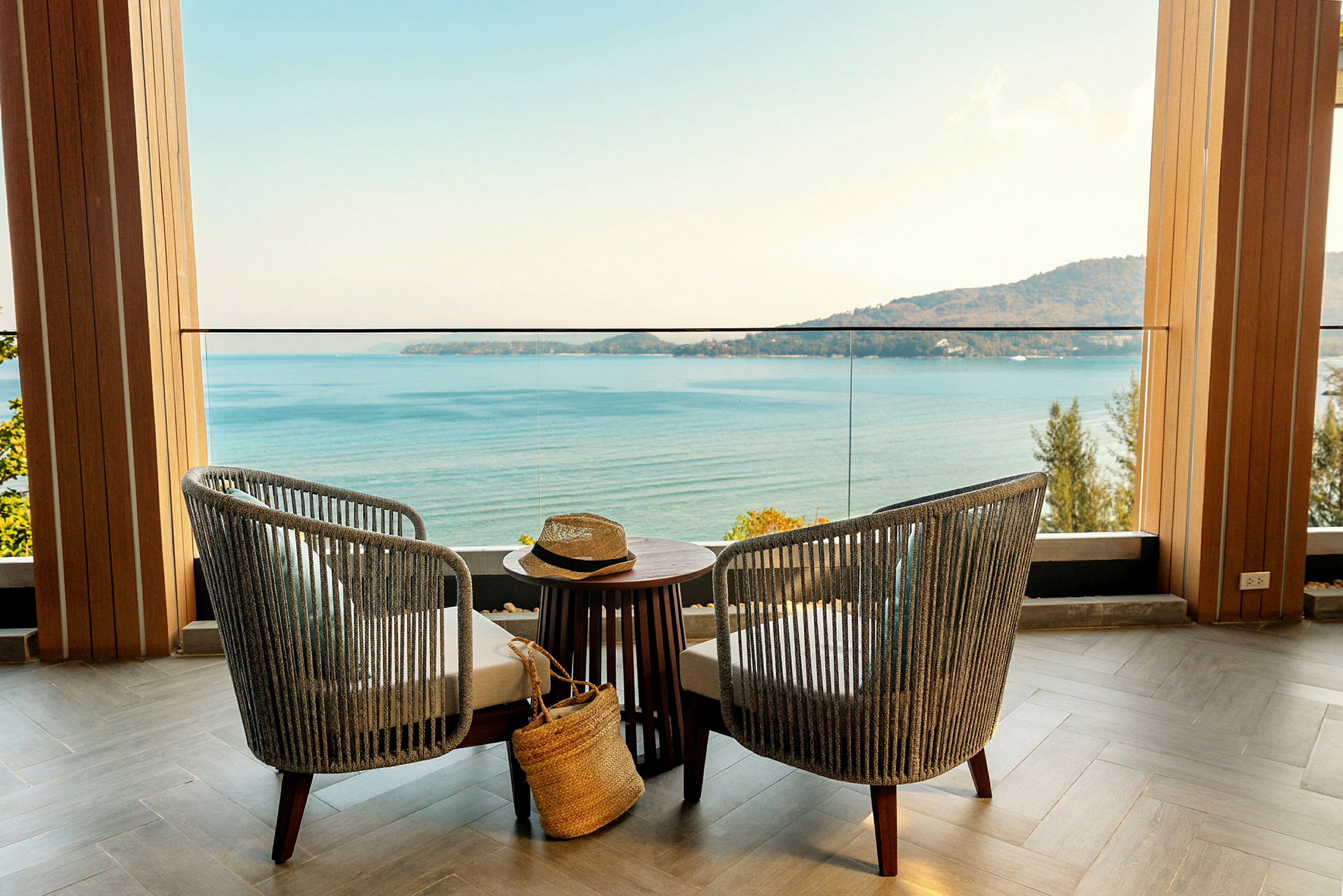 Två stolar och ett bord står på en terrass med utsikt över havet och en bergskust. (AI-genererad text)