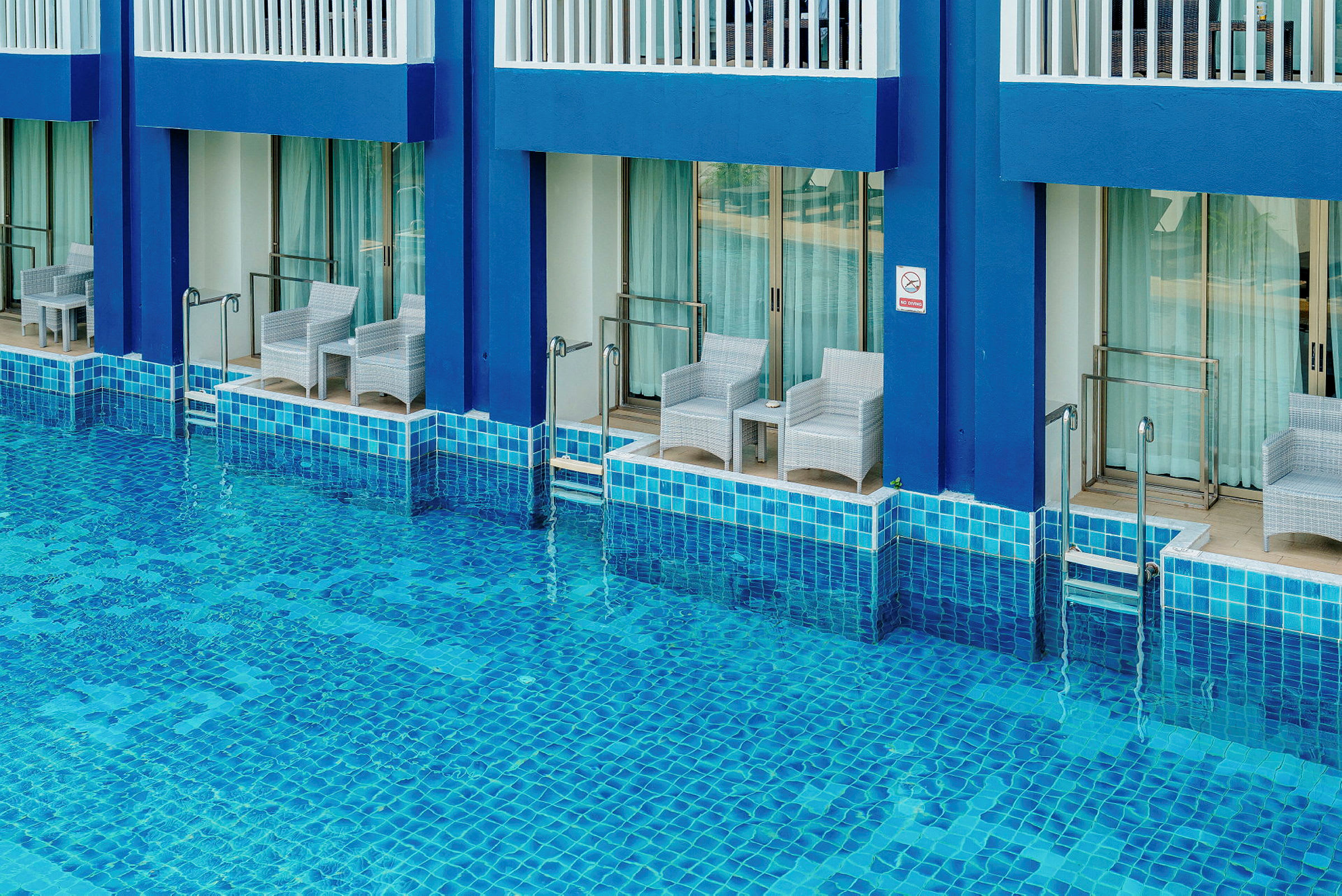 Flera hotellrum med terrasser direkt vid en pool. (AI-genererad text)