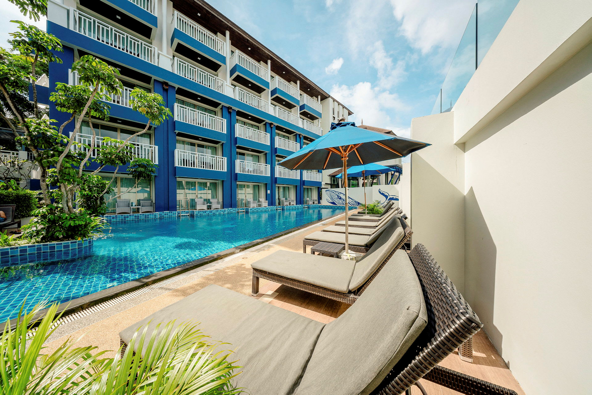 Solstolar vid pool bredvid hotellbygningen. (AI-genererad text)