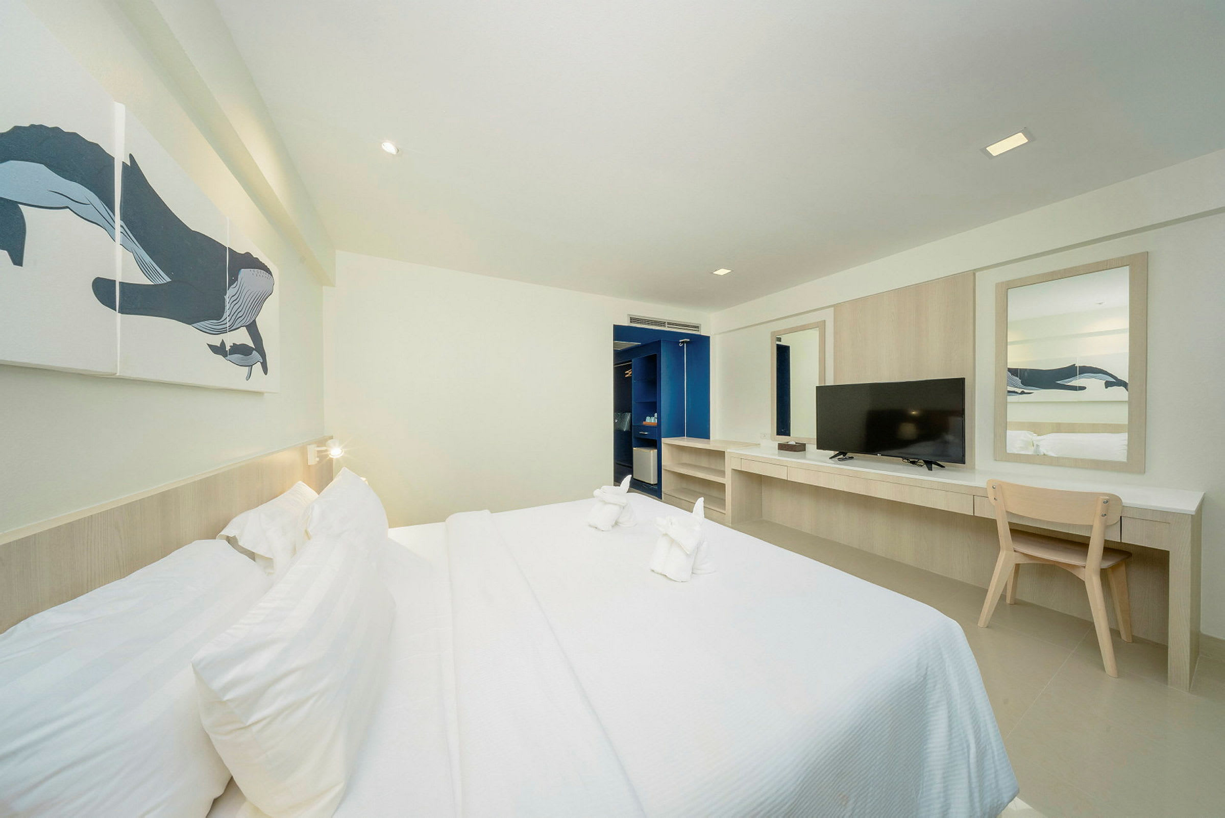 Ett hotellrum med en dubbelsäng, skrivbord, TV och väggkonst. (AI-genererad text)