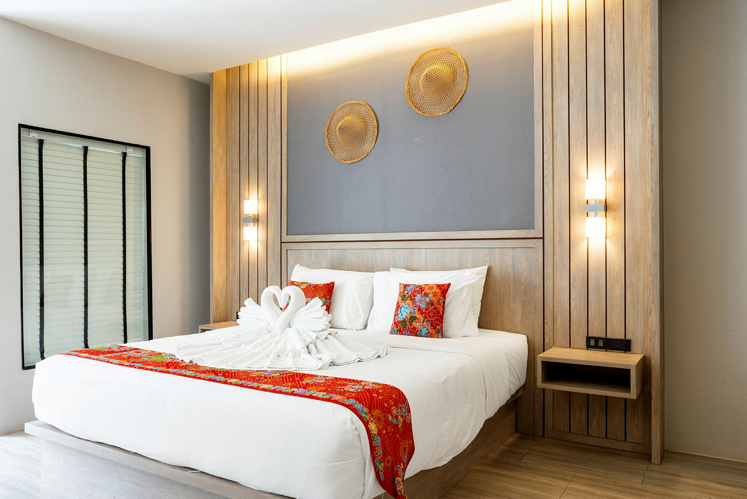 Modern hotellrum med en dubbelsäng dekorerad med svanformade handdukar och röda detaljer. (AI-genererad text)