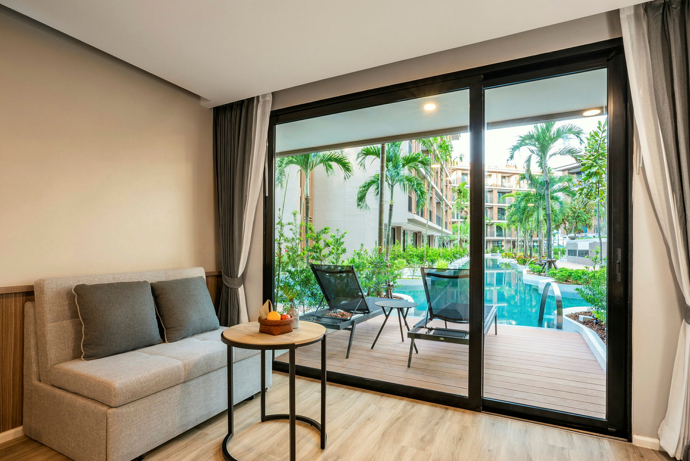 Bild visar en modern hotellsvit med utsikt över en pool och palmer genom glasdörrar. (AI-genererad text)