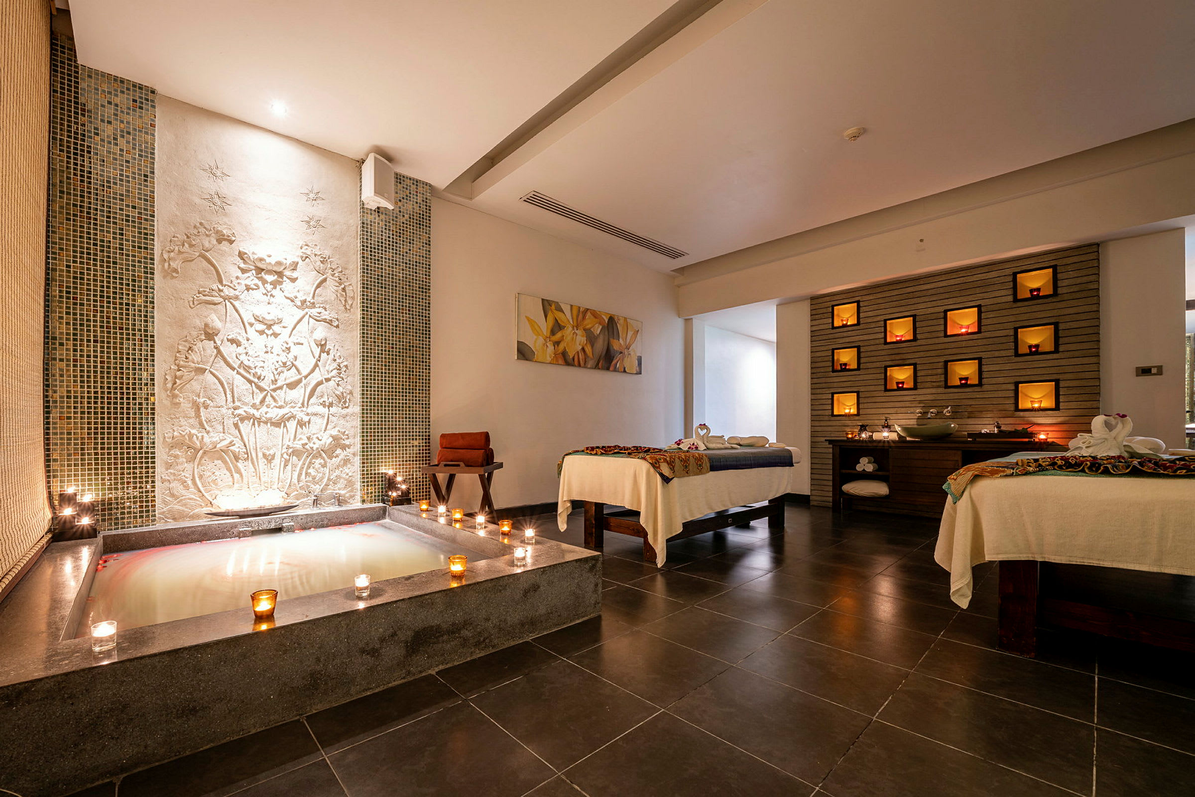 Ett spa-rum med en badpool, dekorationer på väggen och två massagebord. (AI-genererad text)