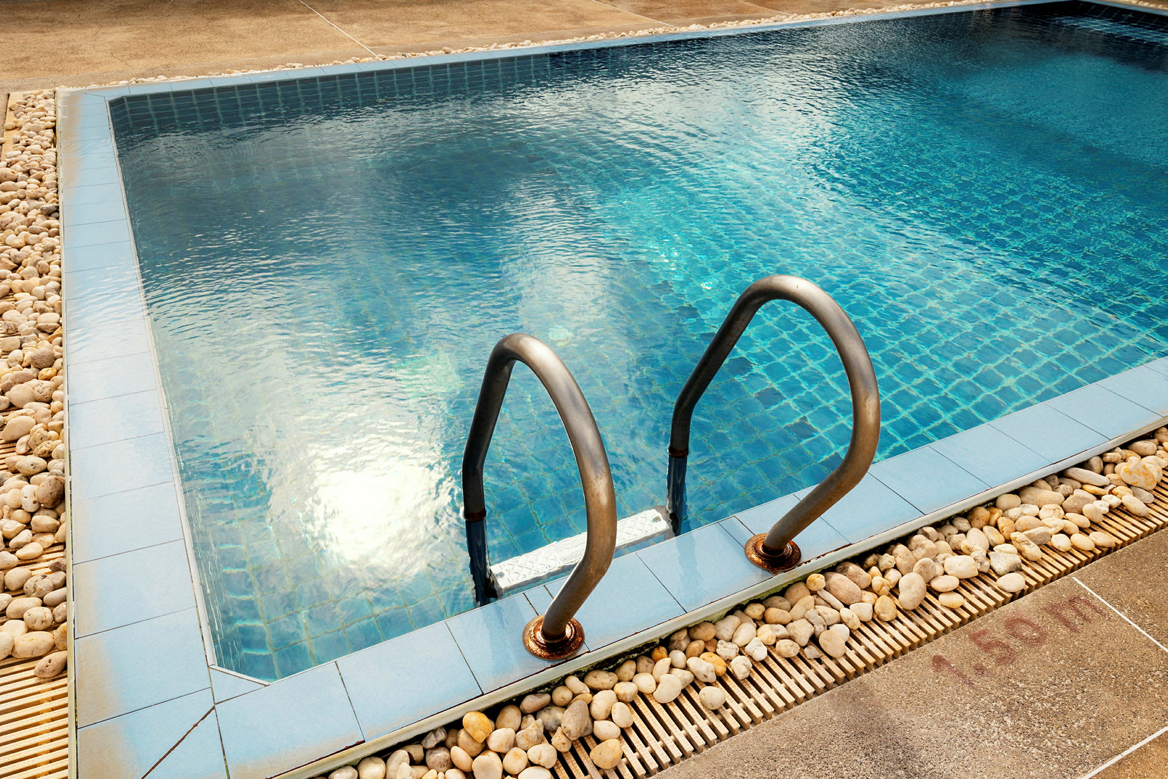 En pool med blå keramikbotten och stålhandtag vid kanten. (AI-genererad text)