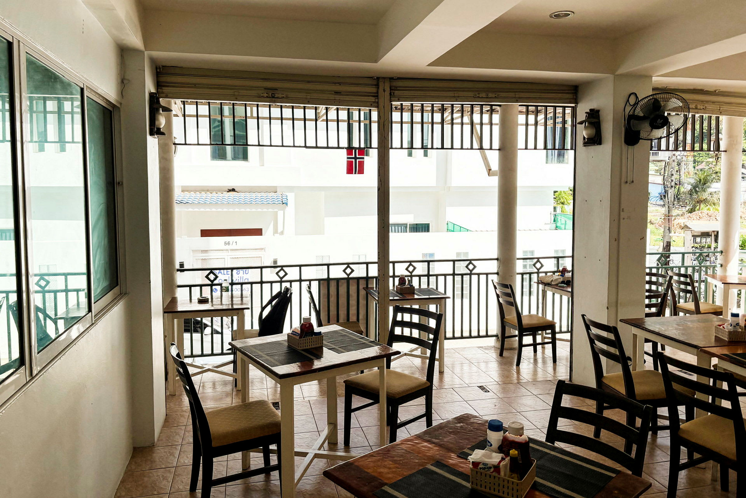 Ett utomhuskafé eller restaurang med bord och stolar, samt vy över en byggnad. (AI-genererad text)