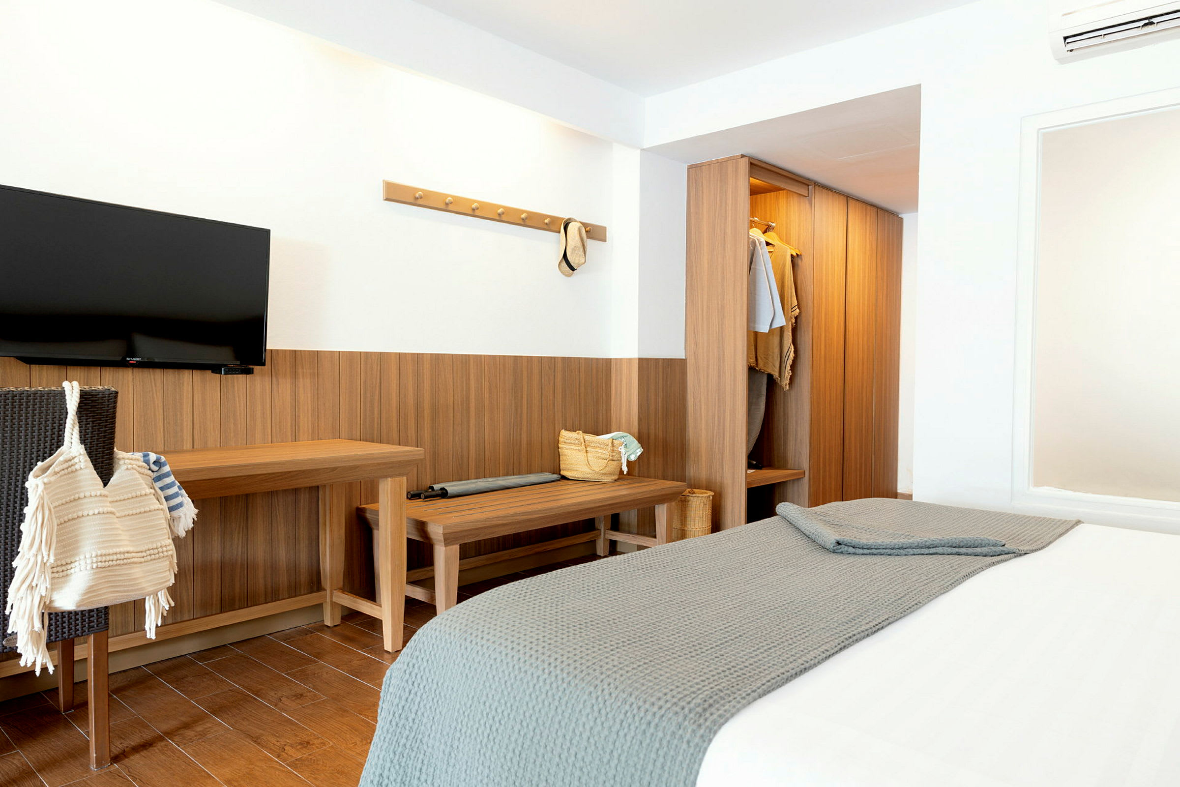 Ett hotellrum med en säng, garderob, och en TV på väggen. (AI-genererad text)
