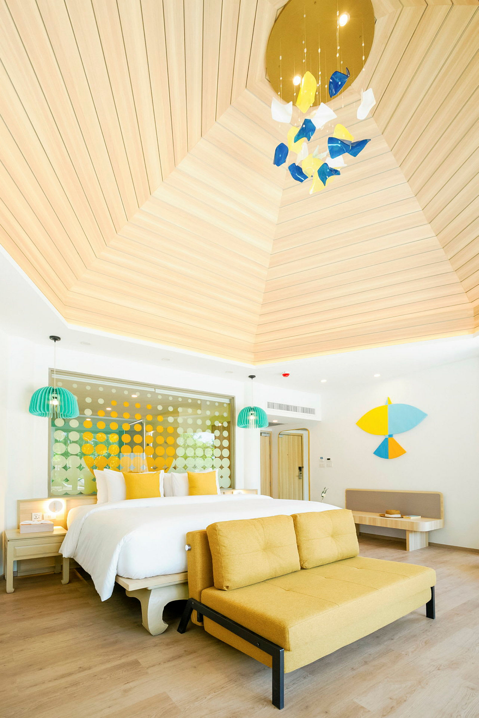 Ett ljust och modernt hotellrum med en stor säng, gul soffa och unika dekorativa element. (AI-genererad text)