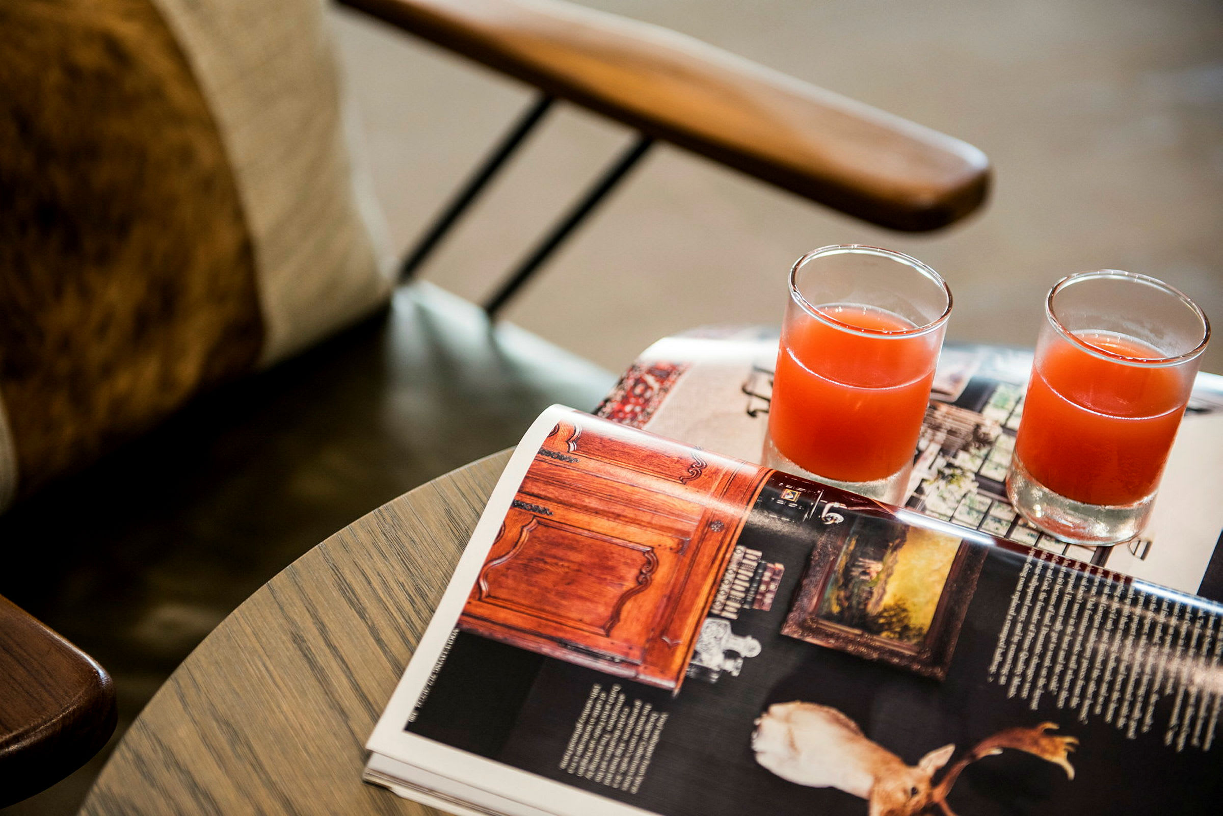 Två glas med röd dryck står på ett bord bredvid en öppen tidning. (AI-genererad text)