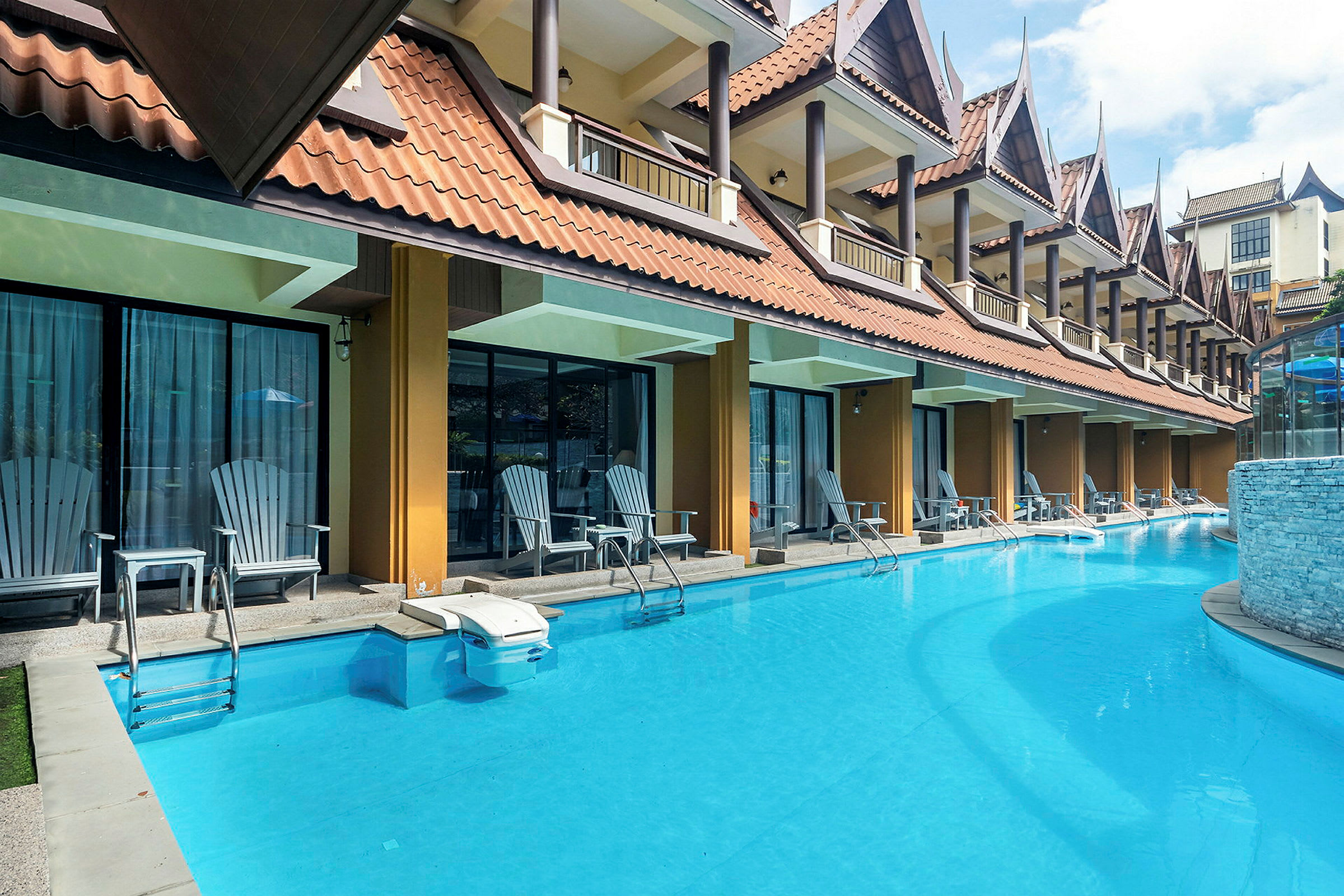 En pool framför en rad hotellrum med uteplatser. (AI-genererad text)
