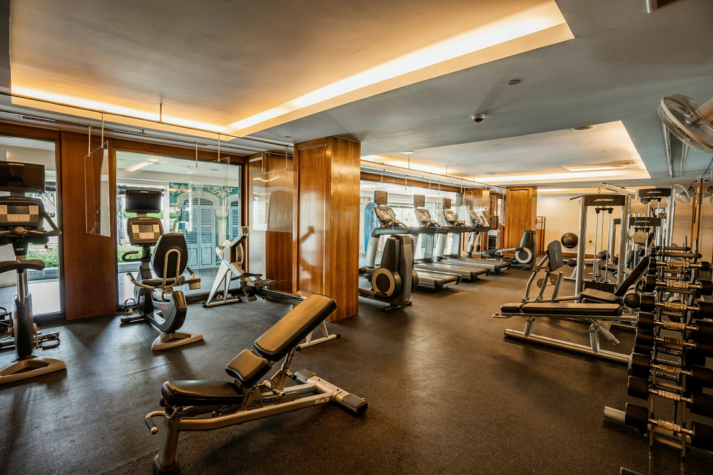 Ett gym med träningsutrustning som löpband, stillastående cyklar, fria vikter och bänkpressbänkar. (AI-genererad text)