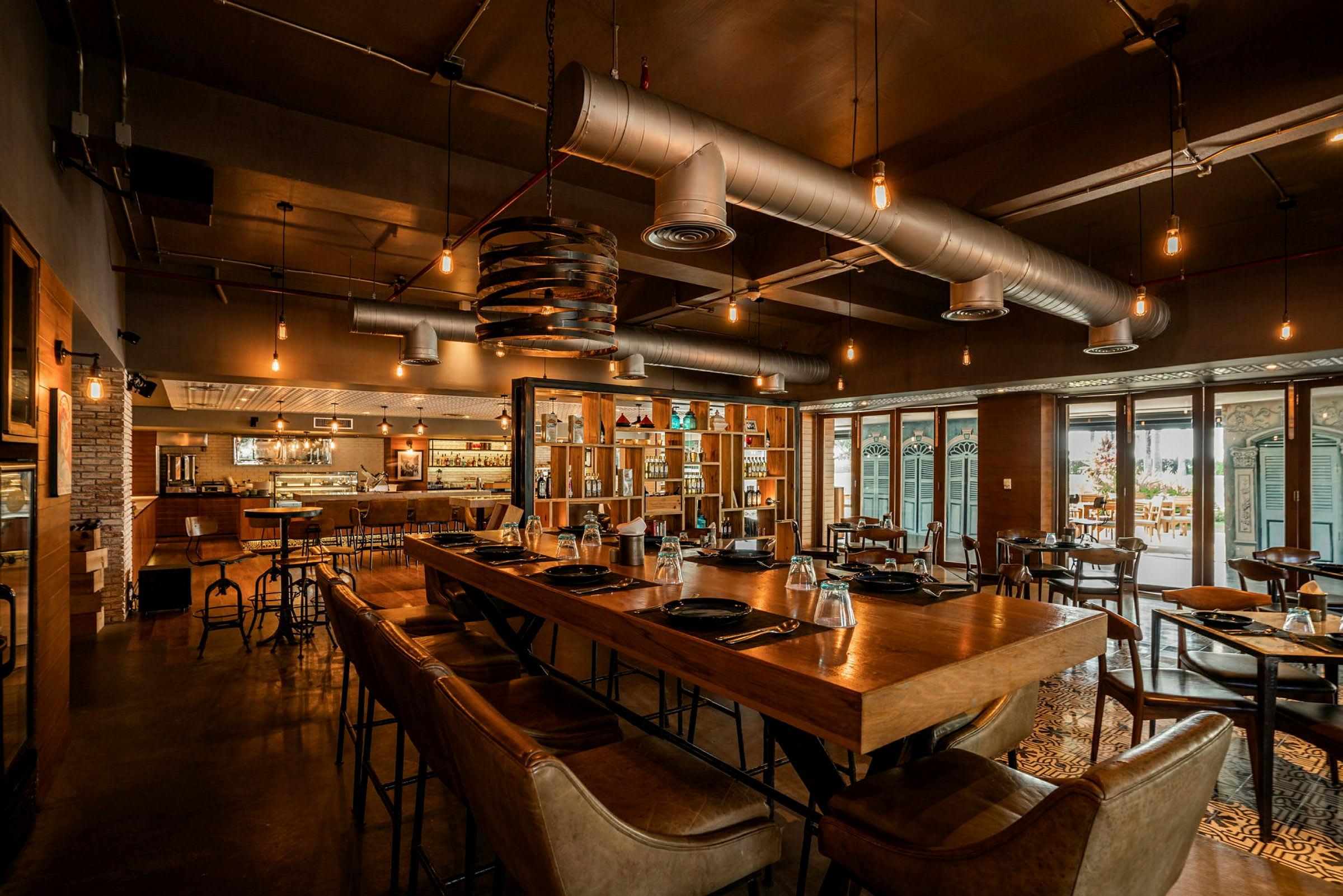 Restaurang med modern inredning, träbord och stolar, upplyst med hängande lampor. (AI-genererad text)