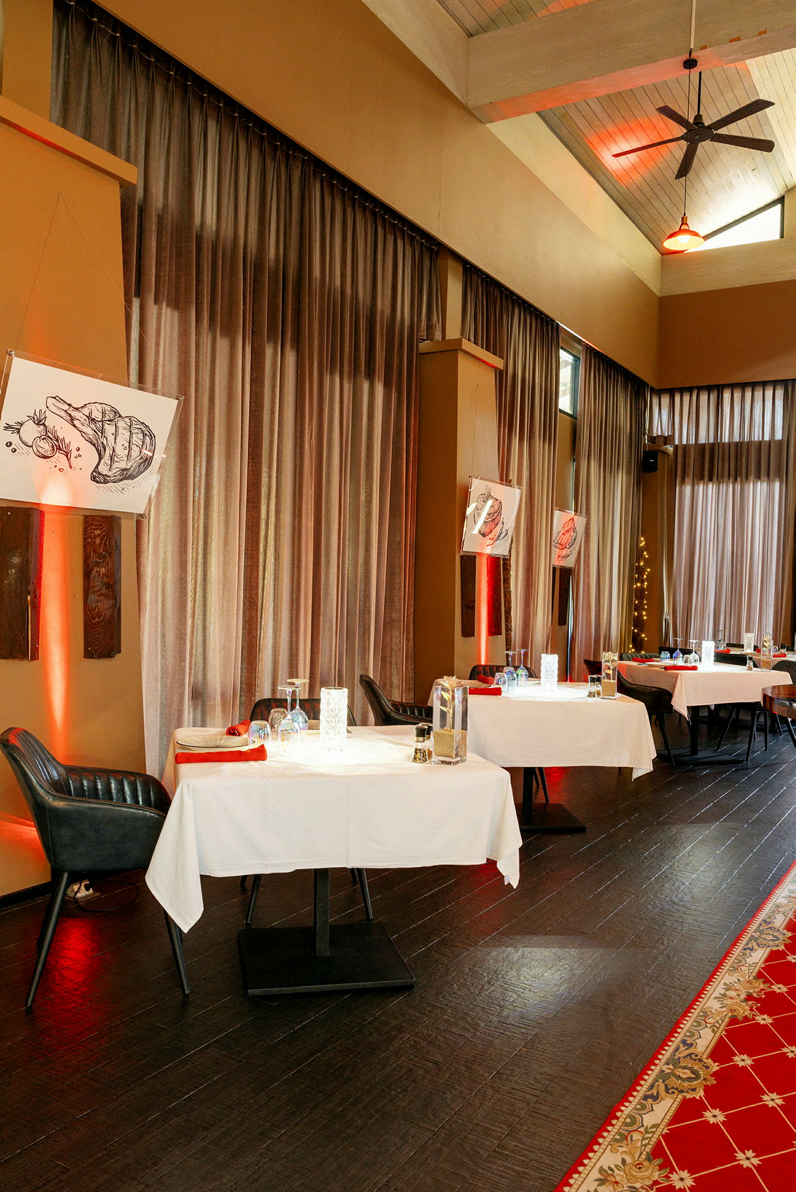 En restaurang med dukade bord, röda servetter och dekorativ belysning. (AI-genererad text)