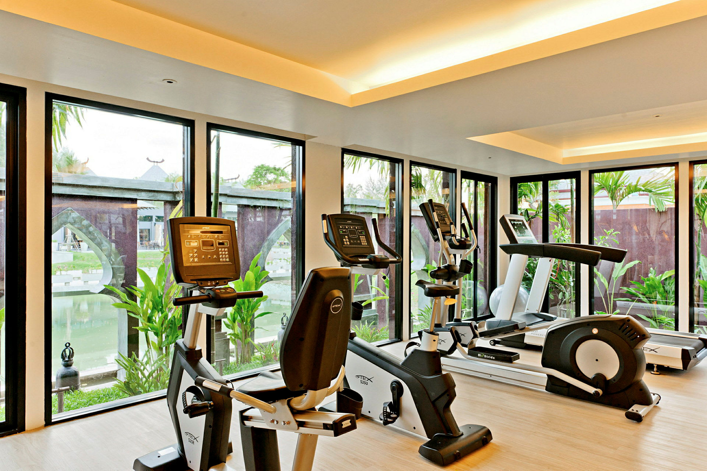 Gym med träningsmaskiner och stora fönster som vetter mot en utomhusmiljö. (AI-genererad text)