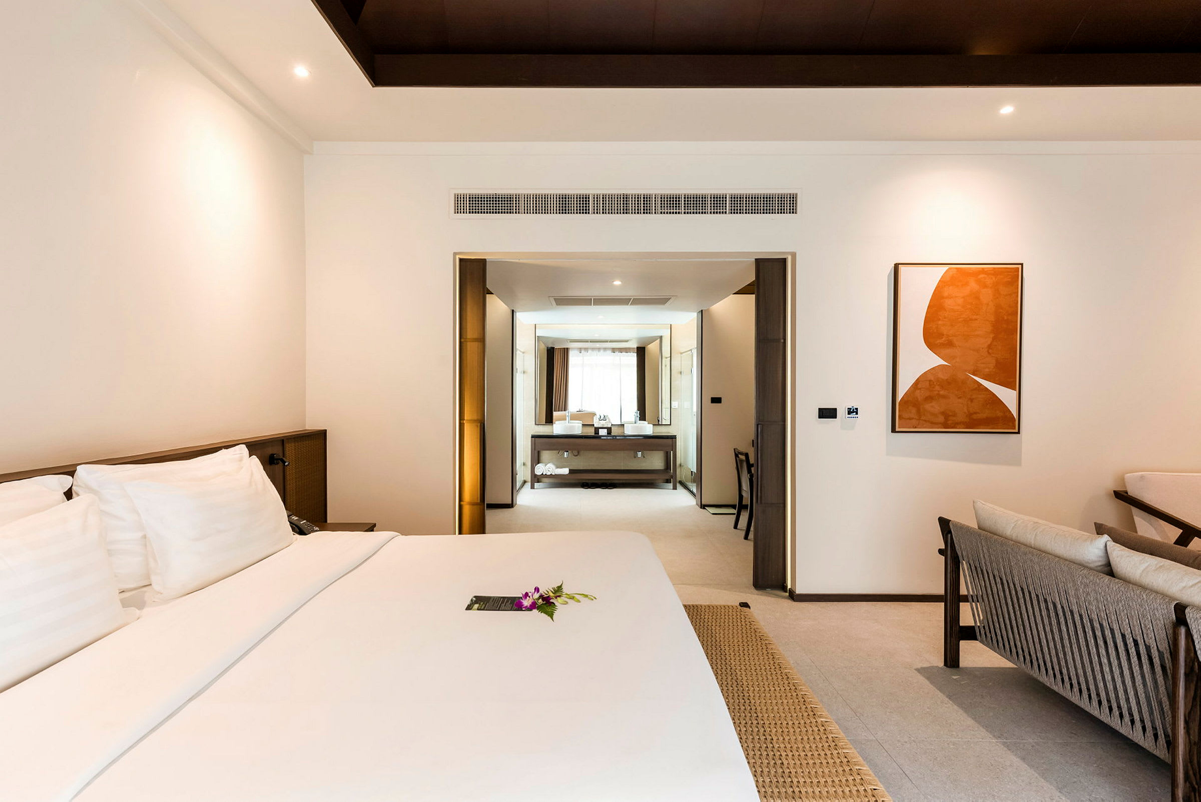 Hotellrum med en stor säng och ett separat badutrymme i bakgrunden. (AI-genererad text)