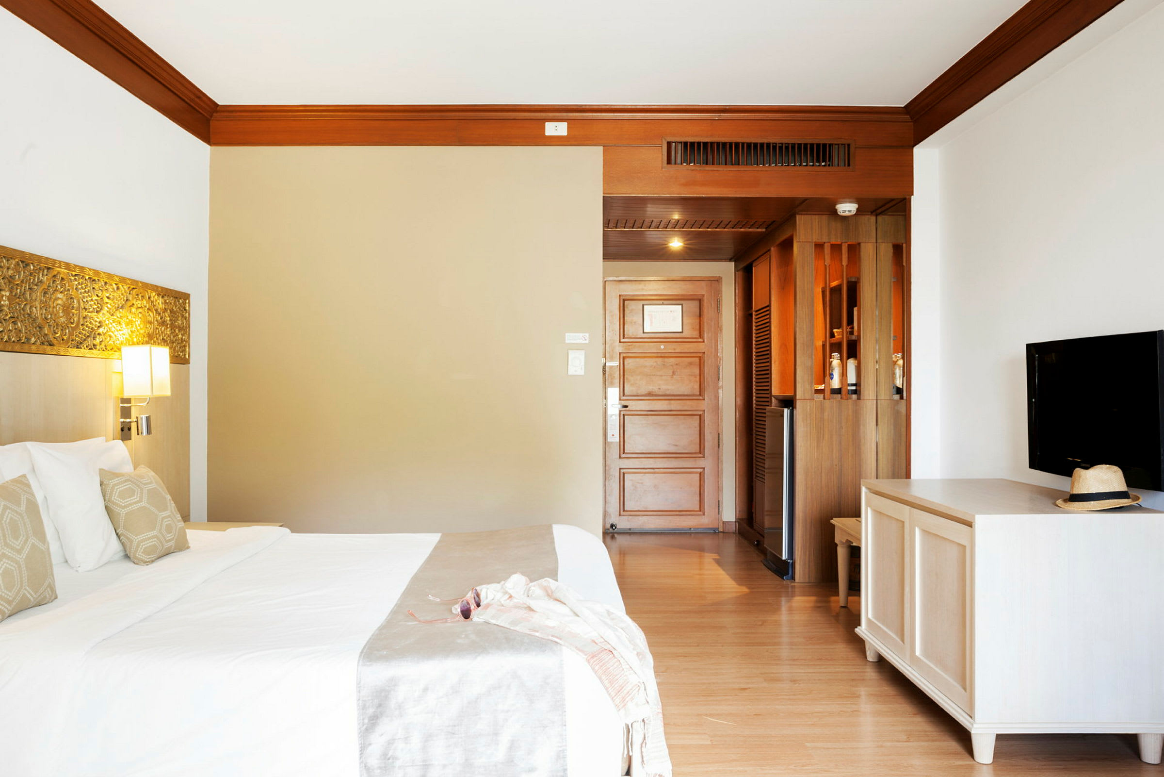 Hotellrum med säng, TV och dörr. (AI-genererad text)