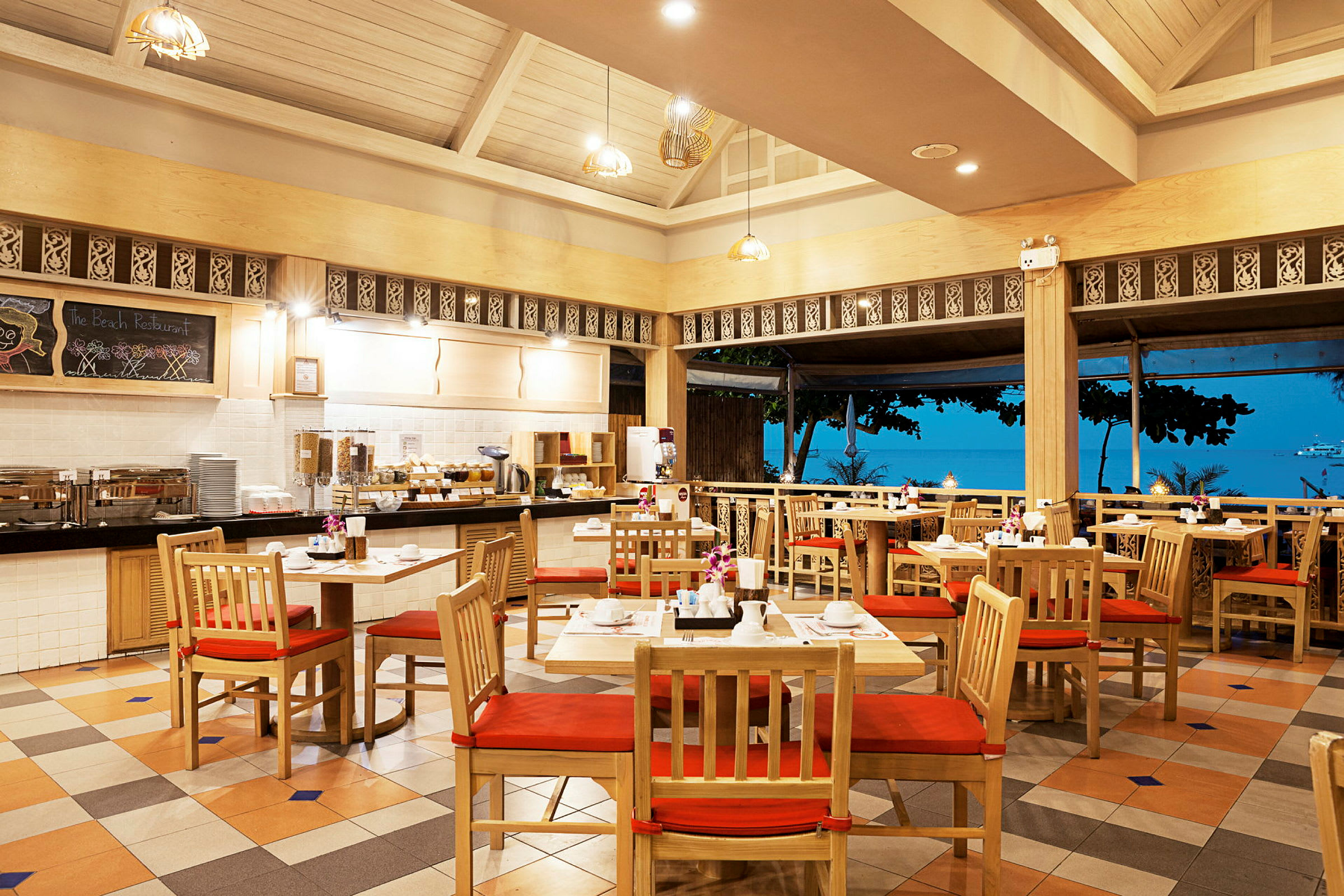 Ett strandnära restaurangområde med trästolar och borden dukade för måltid. (AI-genererad text)