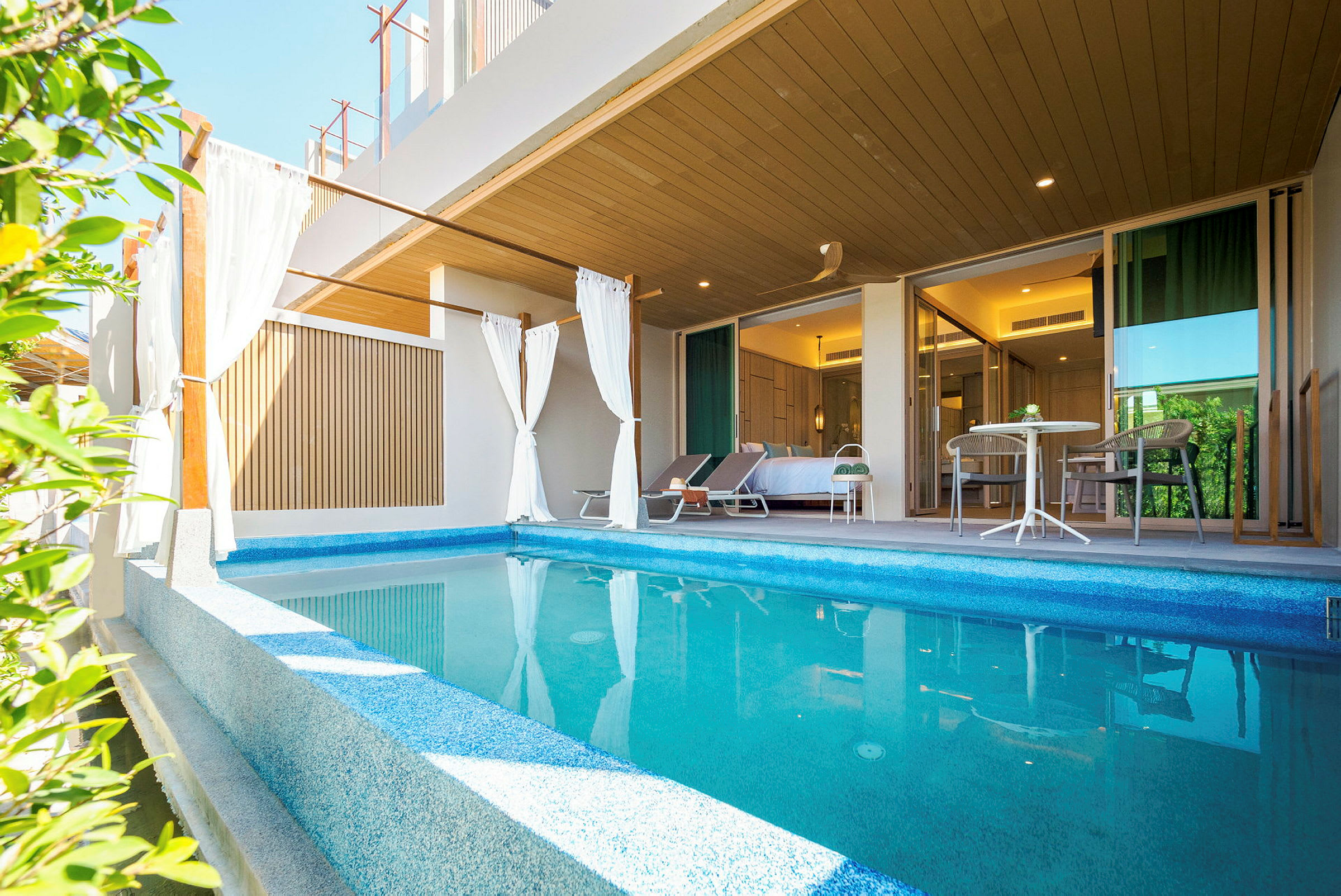 Privat pool med solstolar och sittgrupp framför ett sovrum. (AI-genererad text)