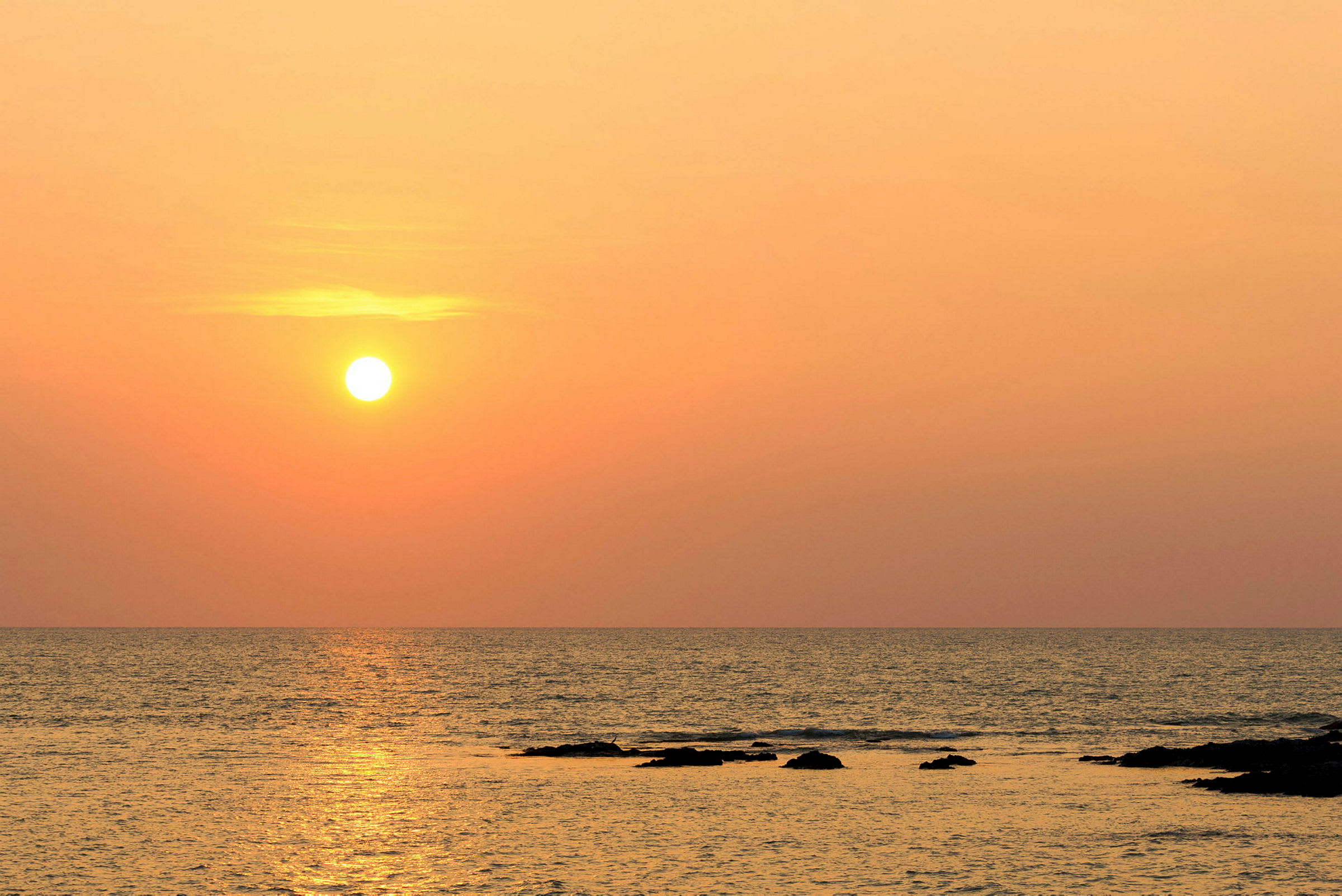 Solnedgång över havet med klippor i vattnet. (AI-genererad text)
