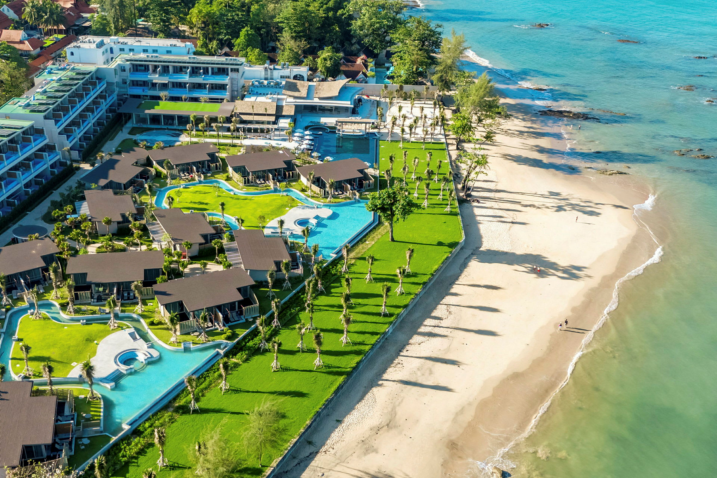 Bild av en resort vid stranden med villaområden och pooler omgivna av grönska. (AI-genererad text)