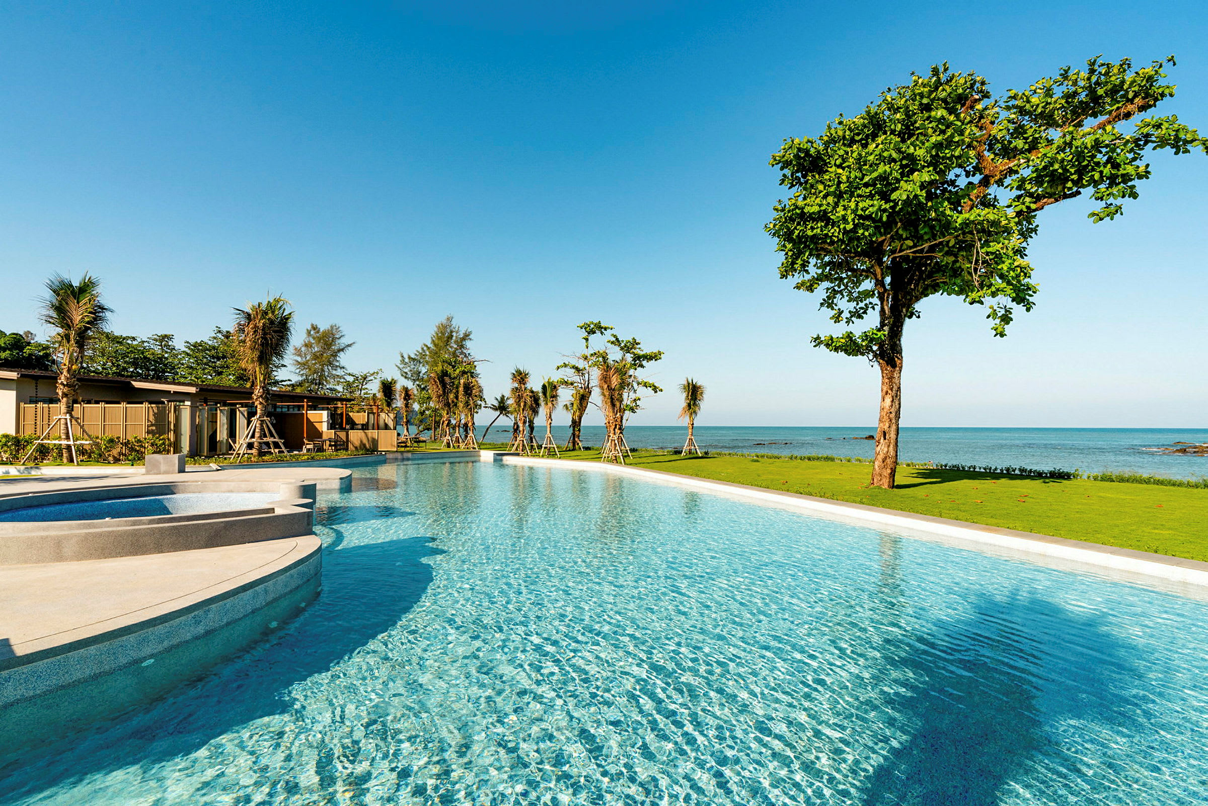 En pool och grönområde vid stranden med havsutsikt. (AI-genererad text)