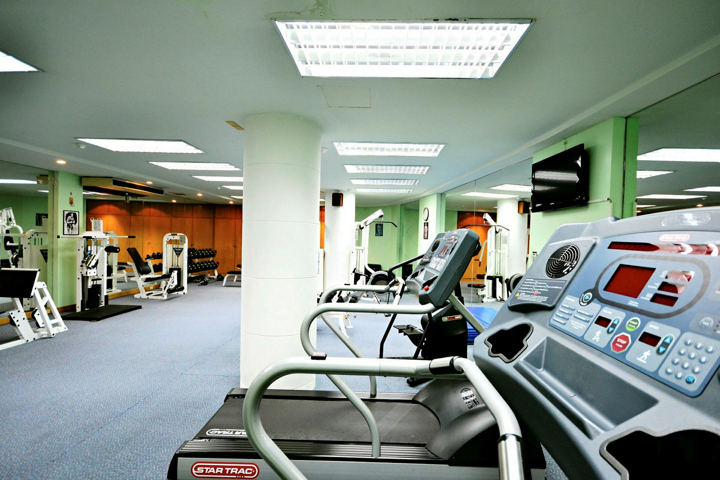 Ett gym med träningsmaskiner inklusive löpband, styrketräningsutrustning och vikter. (AI-genererad text)
