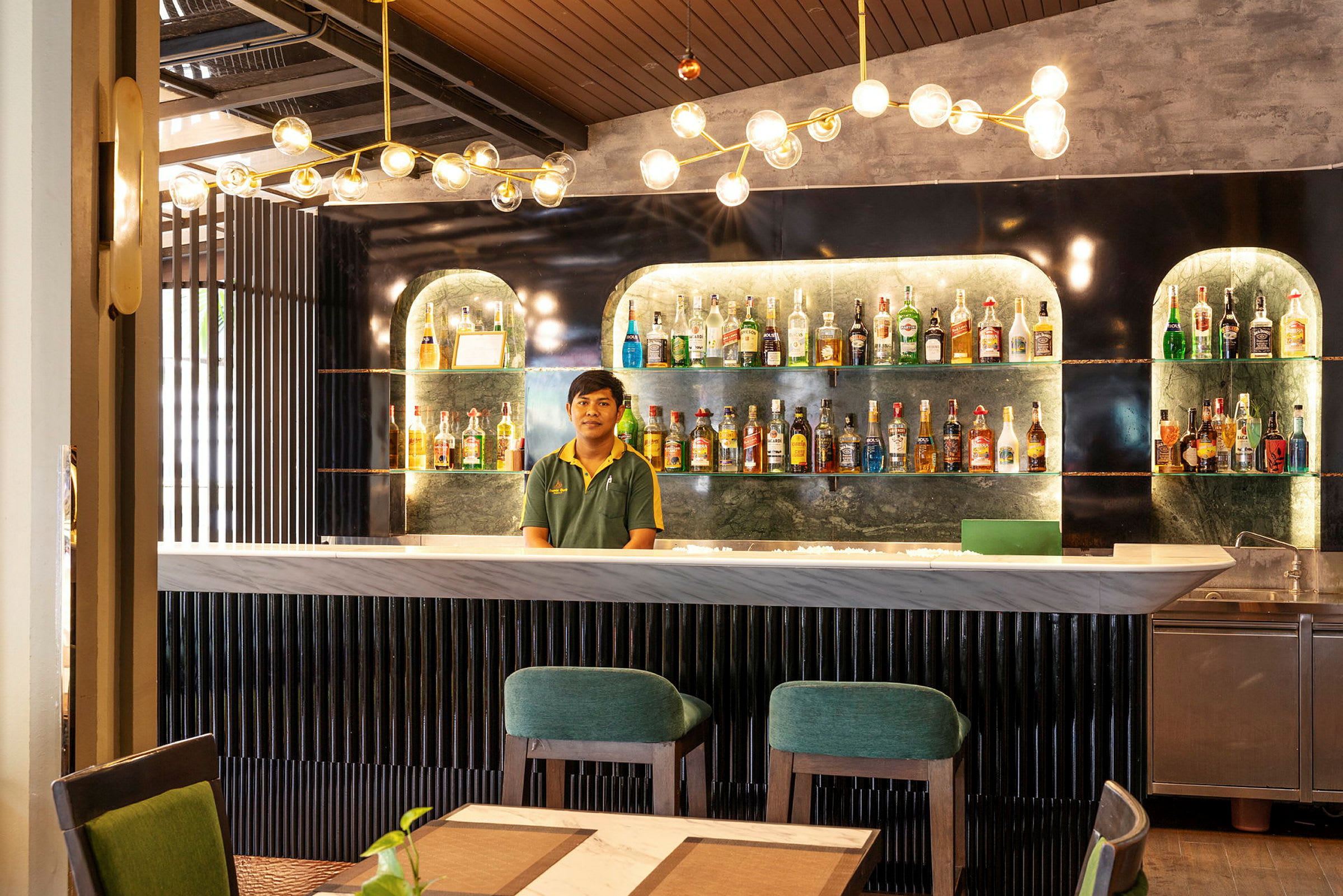 En modern bar med flaskor uppställda på hyllor och moderna möbler. (AI-genererad text)