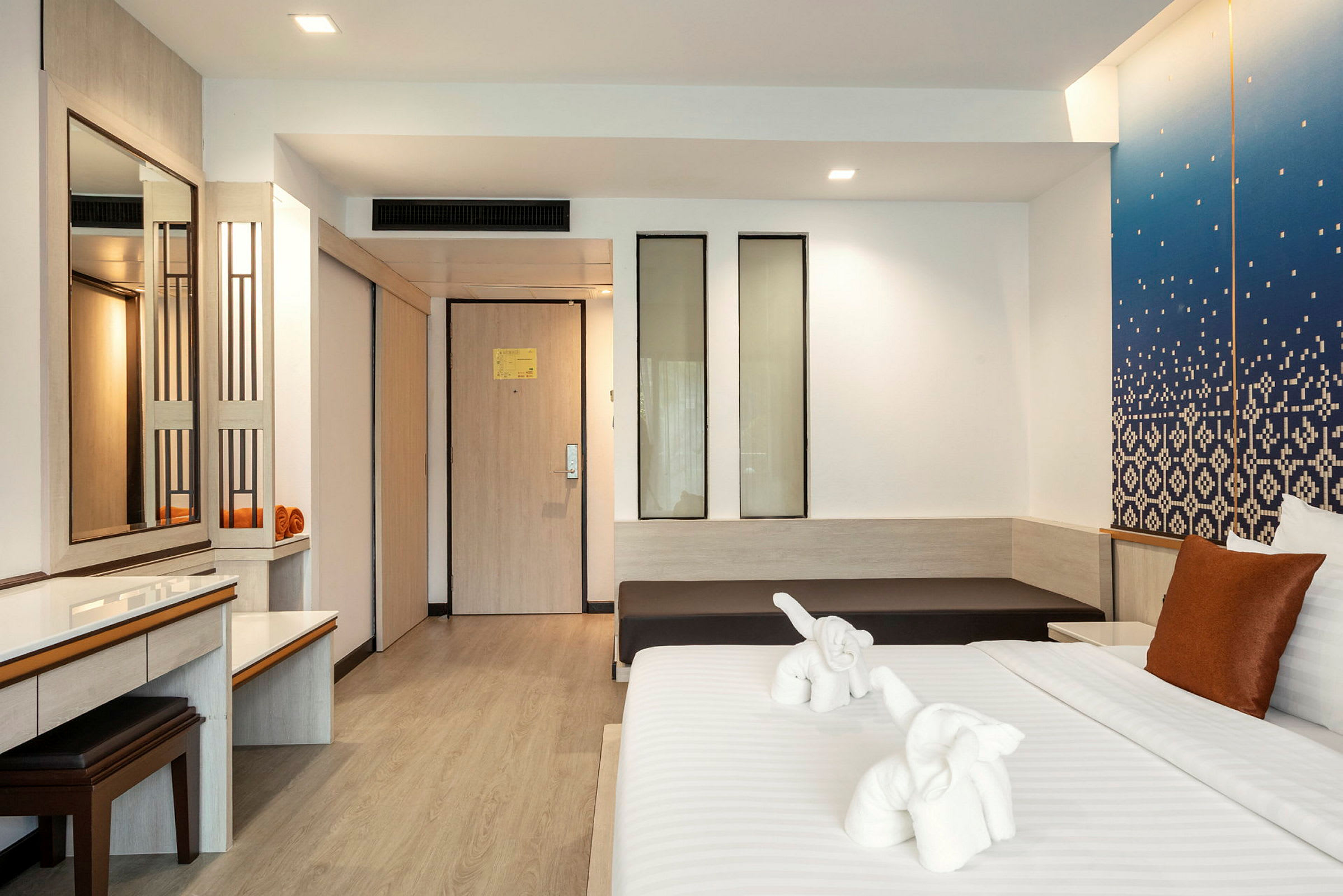 Ett hotellrum med en säng som har två handduksskulpturer formade som elefanter. (AI-genererad text)