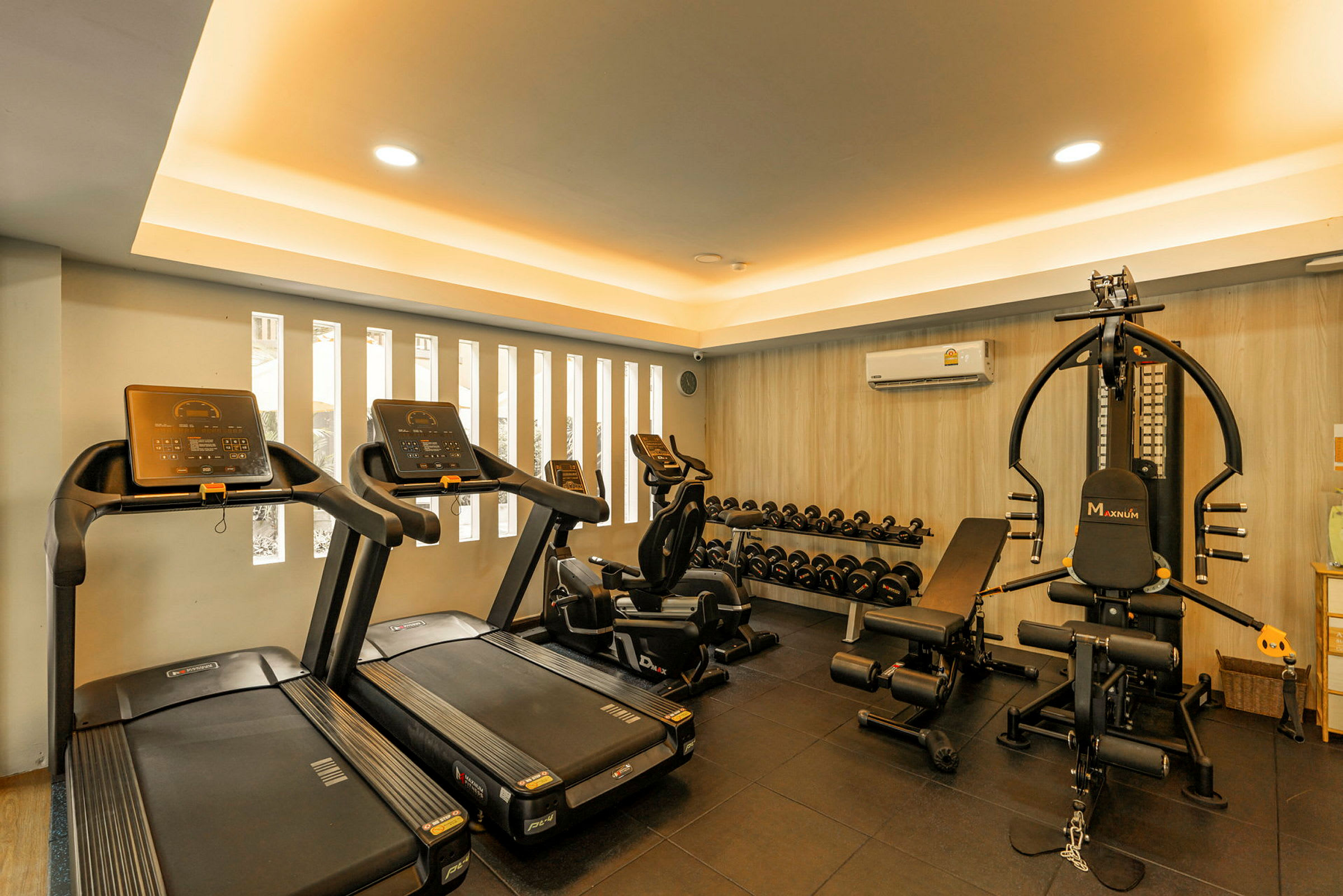 Ett modernt gym med löpband, träningscyklar, viktmaskiner och en rad hantlar. (AI-genererad text)