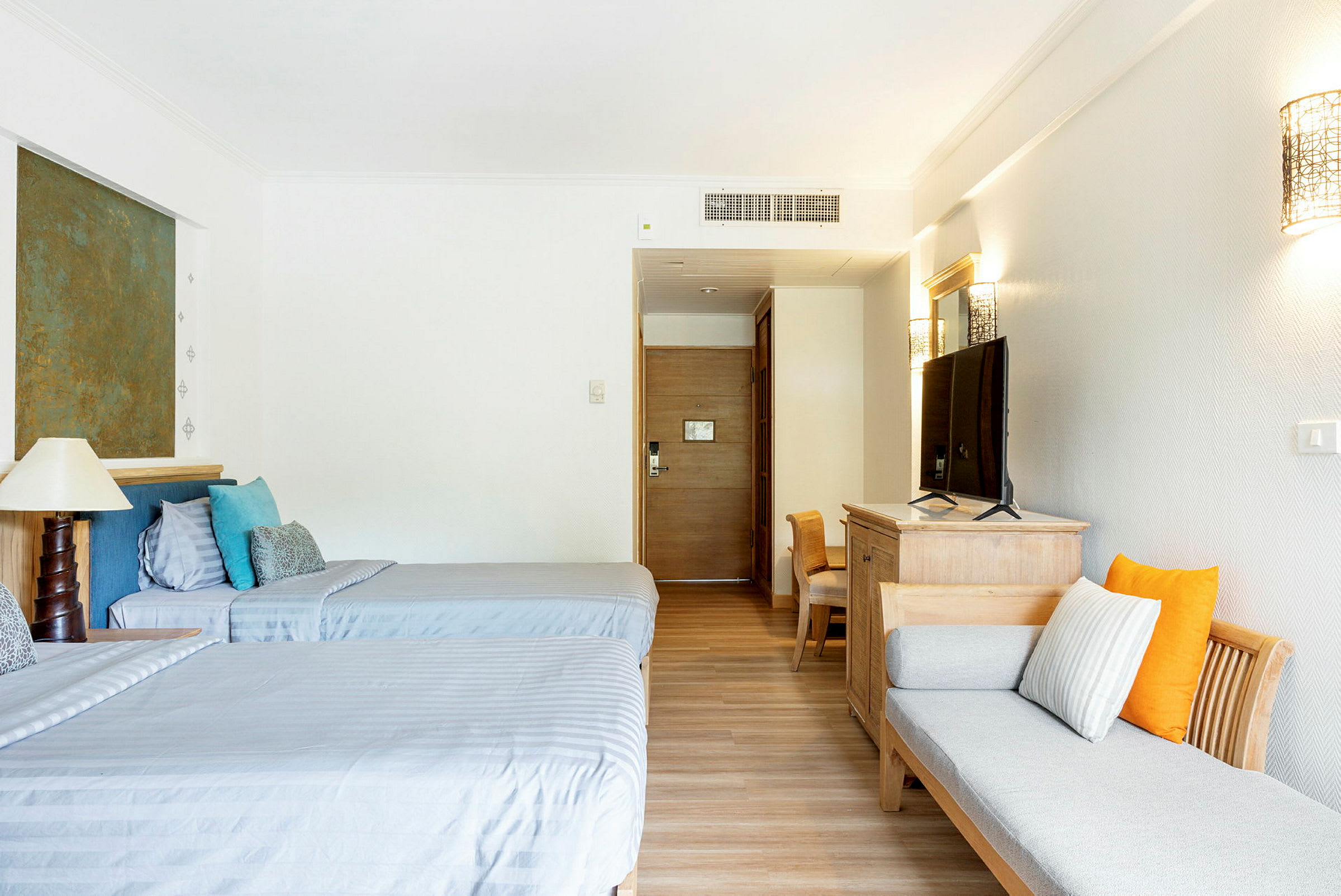Ett hotellrum med två enkelsängar, en soffa, och en TV på en byrå. (AI-genererad text)