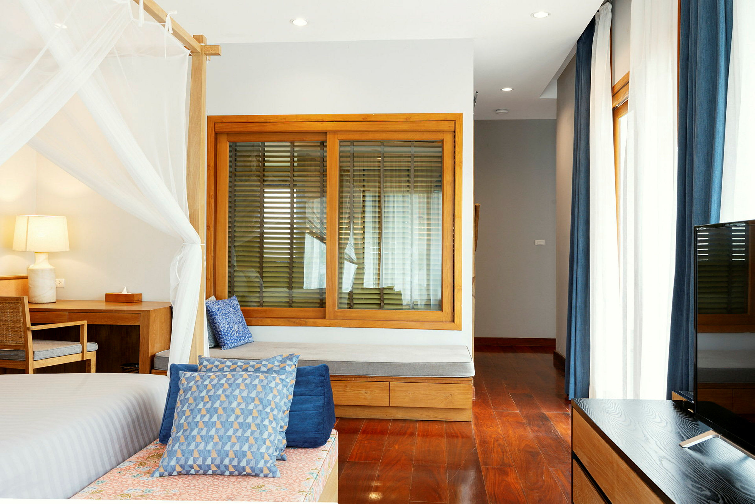 Ett ljust och modernt hotellrum med trädetaljer och blå accenter. (AI-genererad text)