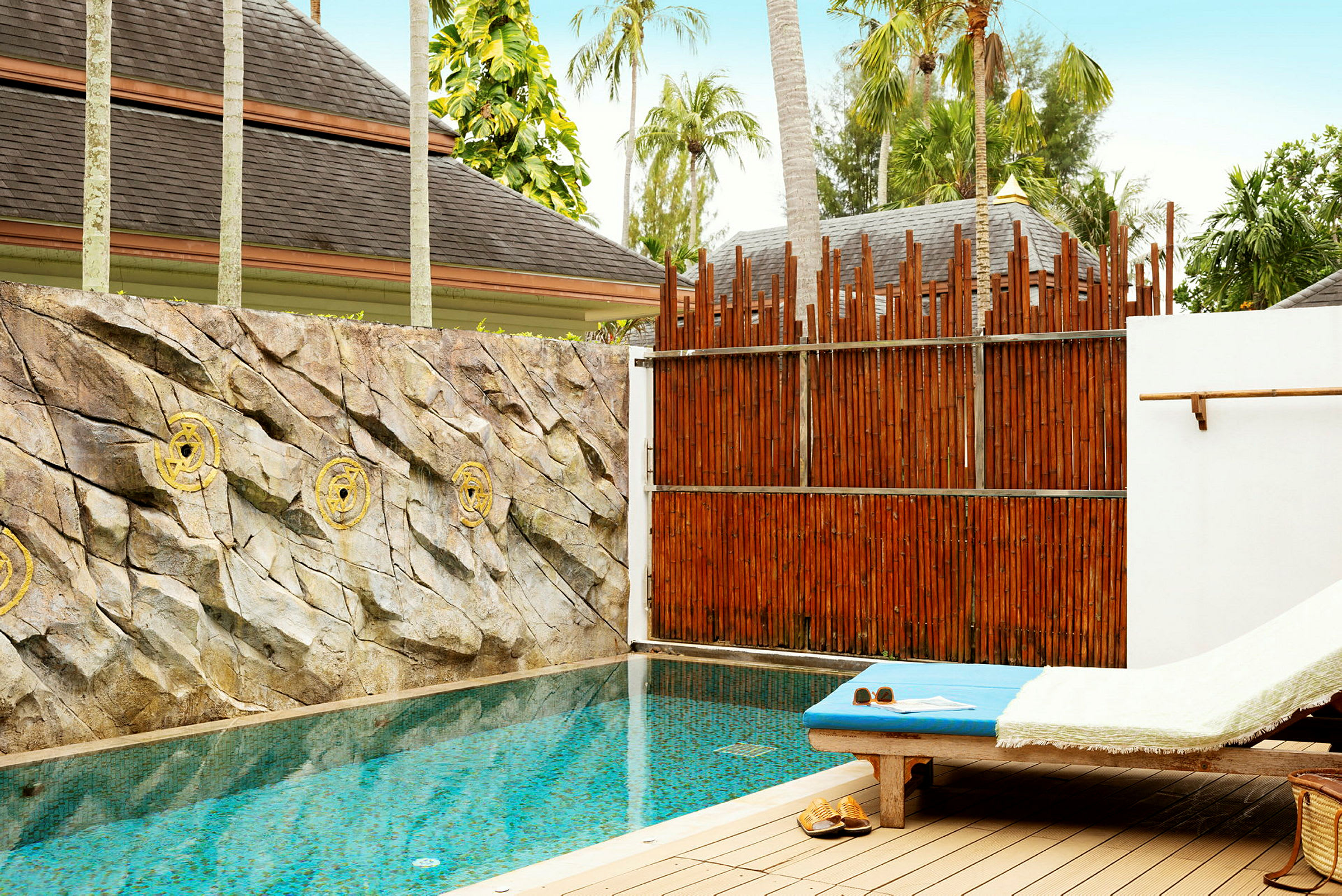 En privat pool med solstol bredvid och stenar pryder väggen bakom poolen. (AI-genererad text)