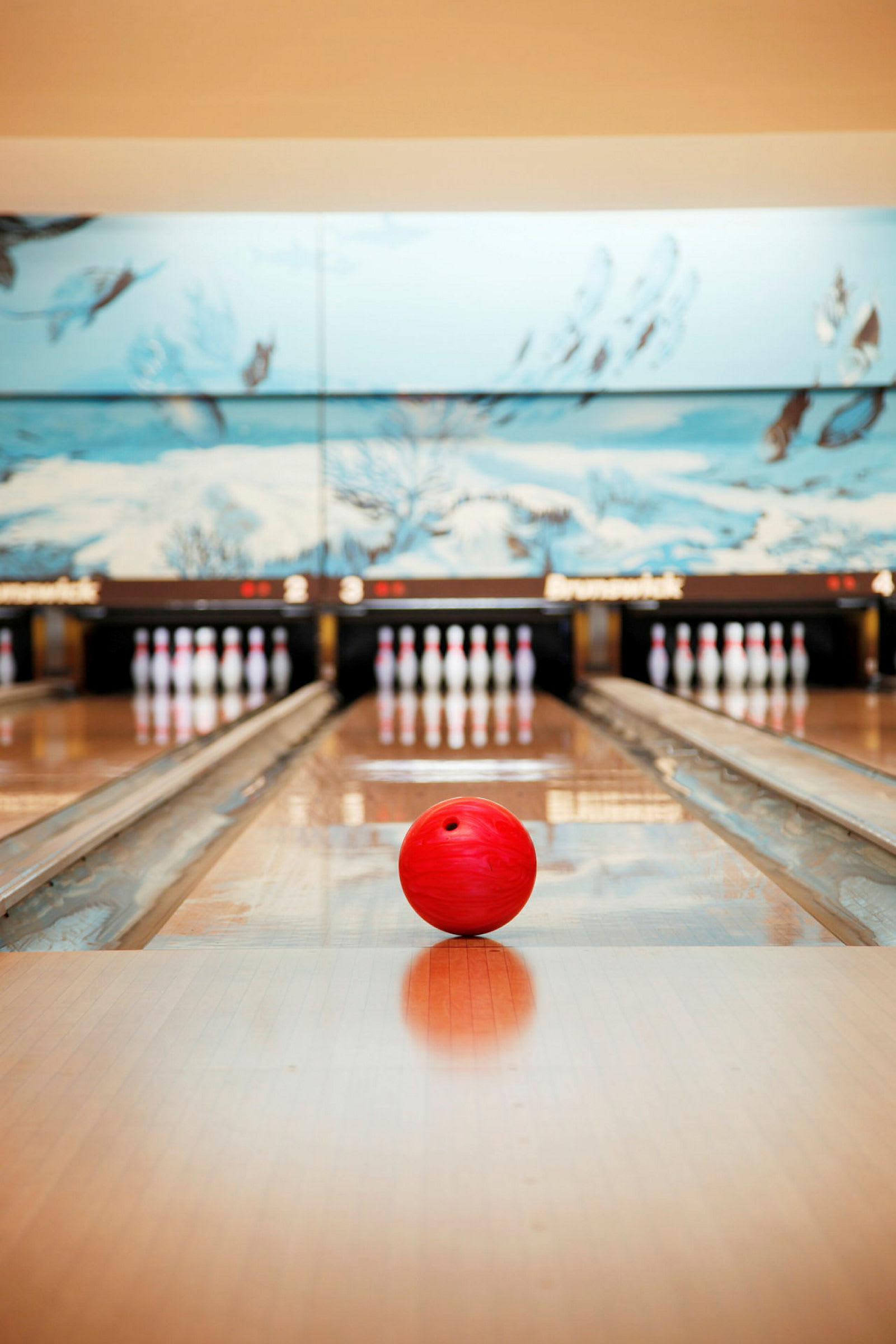 En röd bowlingklot ligger på en bowlingbana, med käglor i bakgrunden. (AI-genererad text)