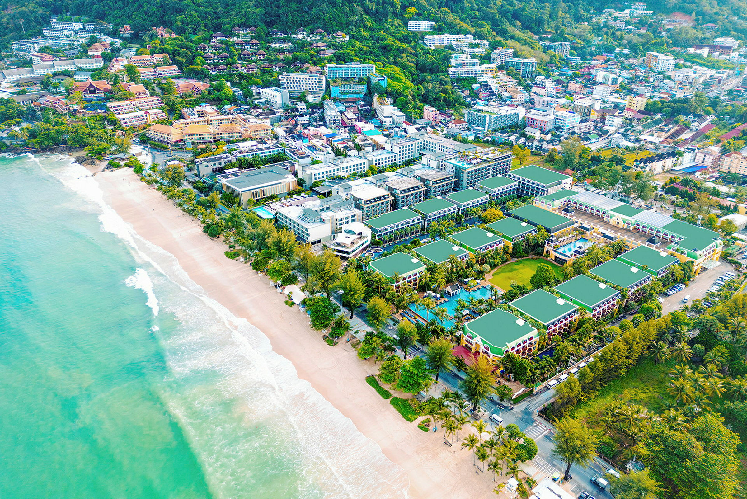 Flygfoto av en kuststad med byggnader och gröna områden vid en strand. (AI-genererad text)