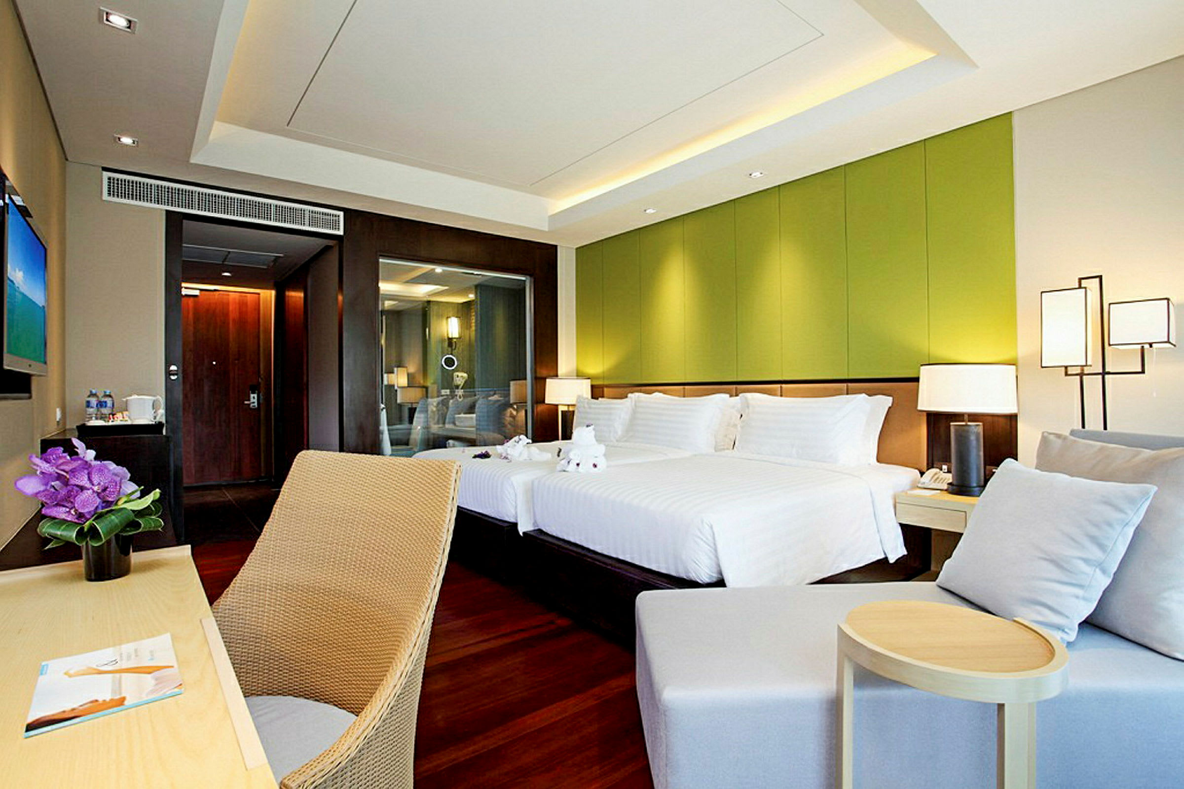 Ett hotellrum med två bäddar, en grön väggpanel och en skrivbordstol. (AI-genererad text)