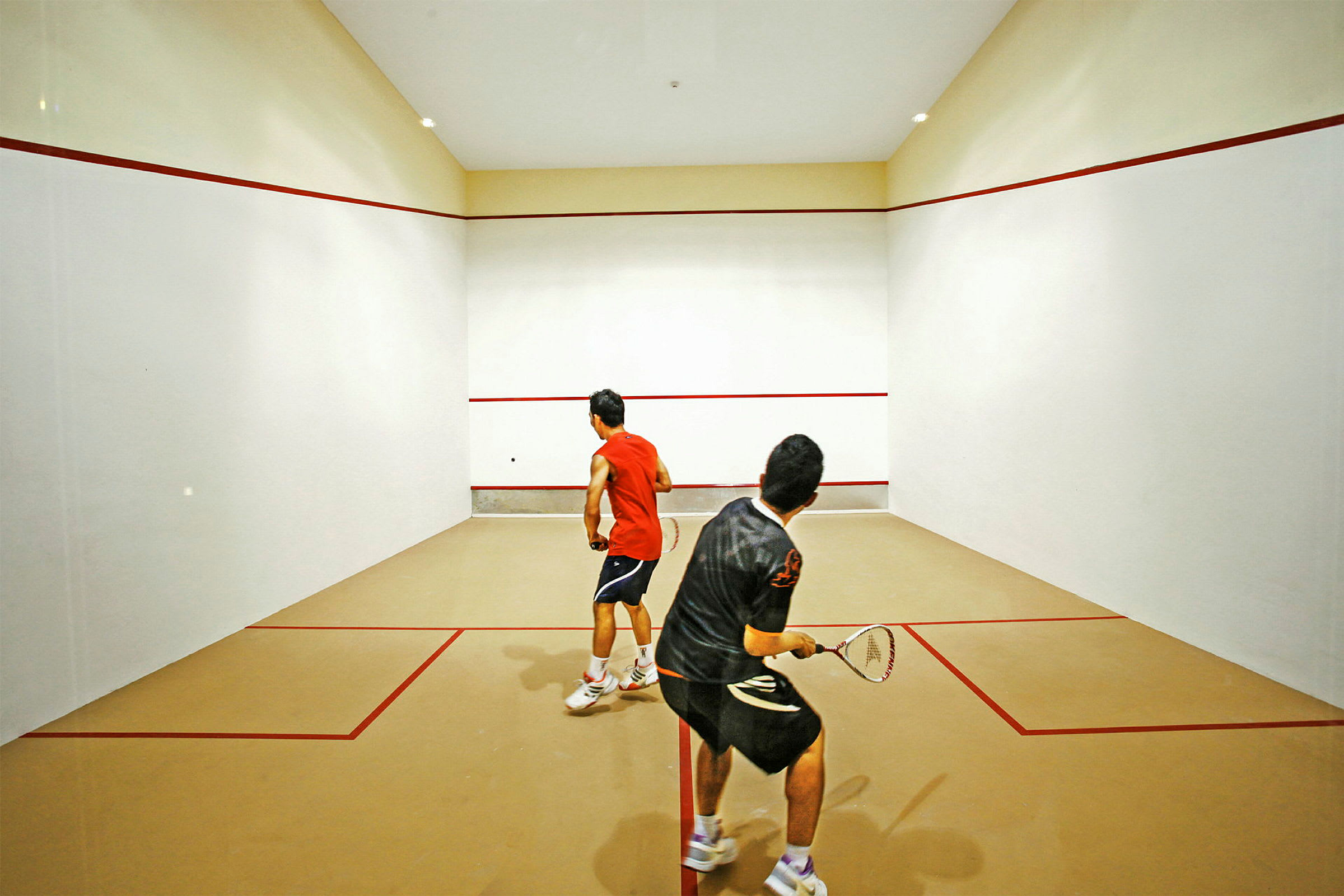 Två personer spelar squash på en inomhusbana. (AI-genererad text)
