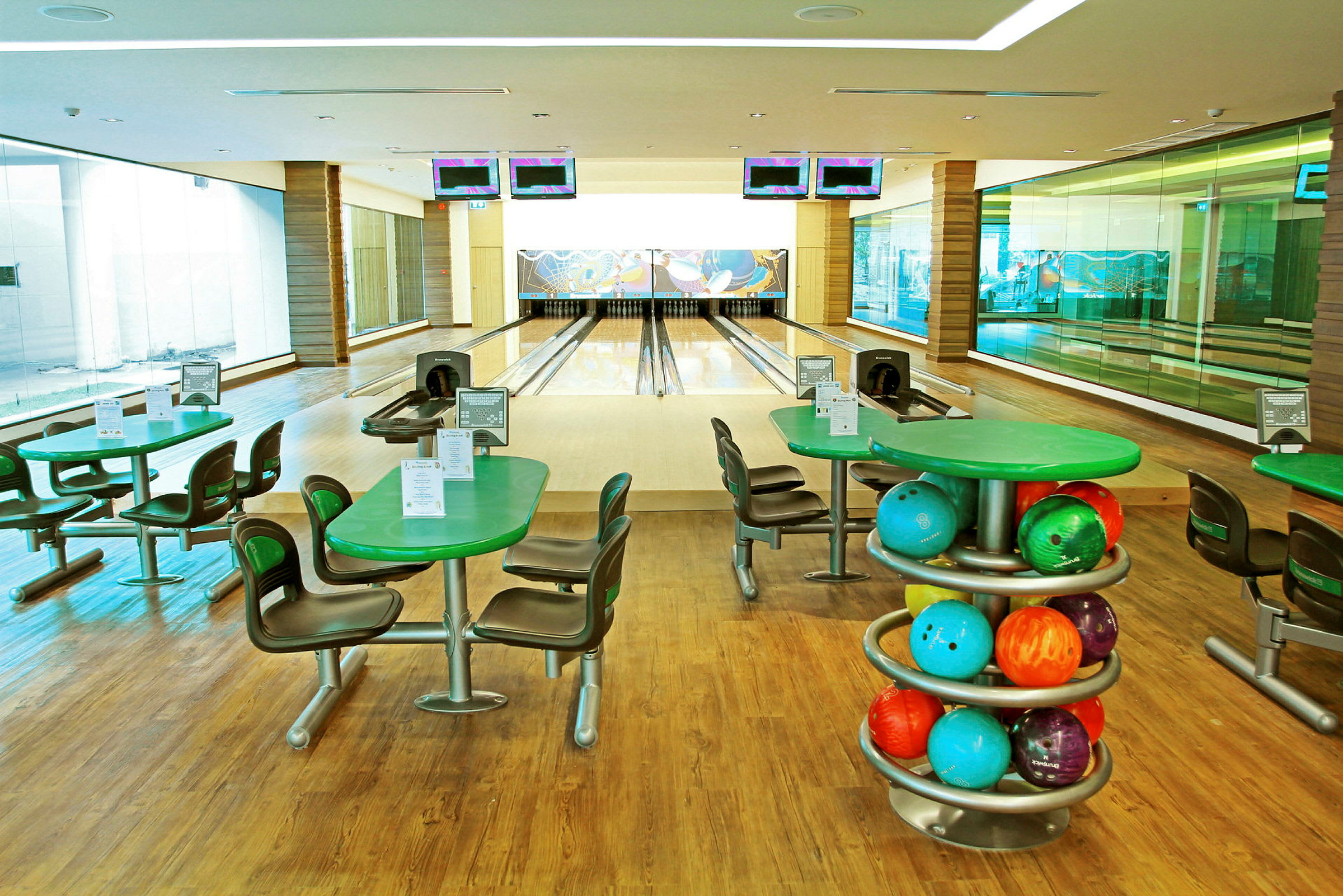 En bowlinghall med fyra bowlingbanor, bord och stolar samt färgglada bowlingklot. (AI-genererad text)