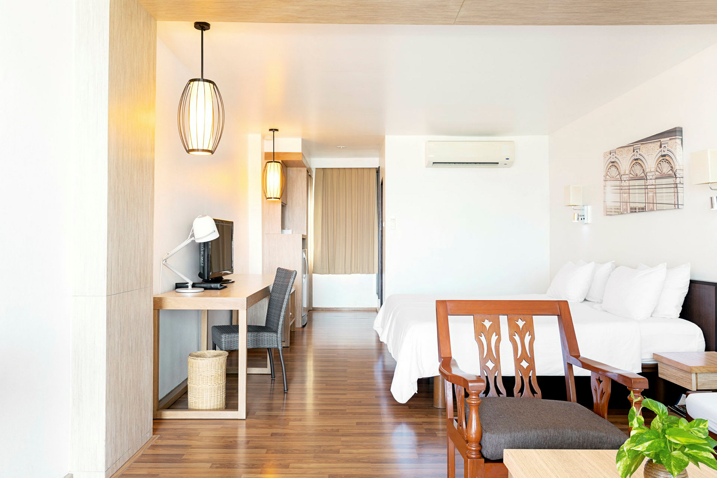 Hotellrum med dubbelsäng, skrivbord, TV och stol. (AI-genererad text)