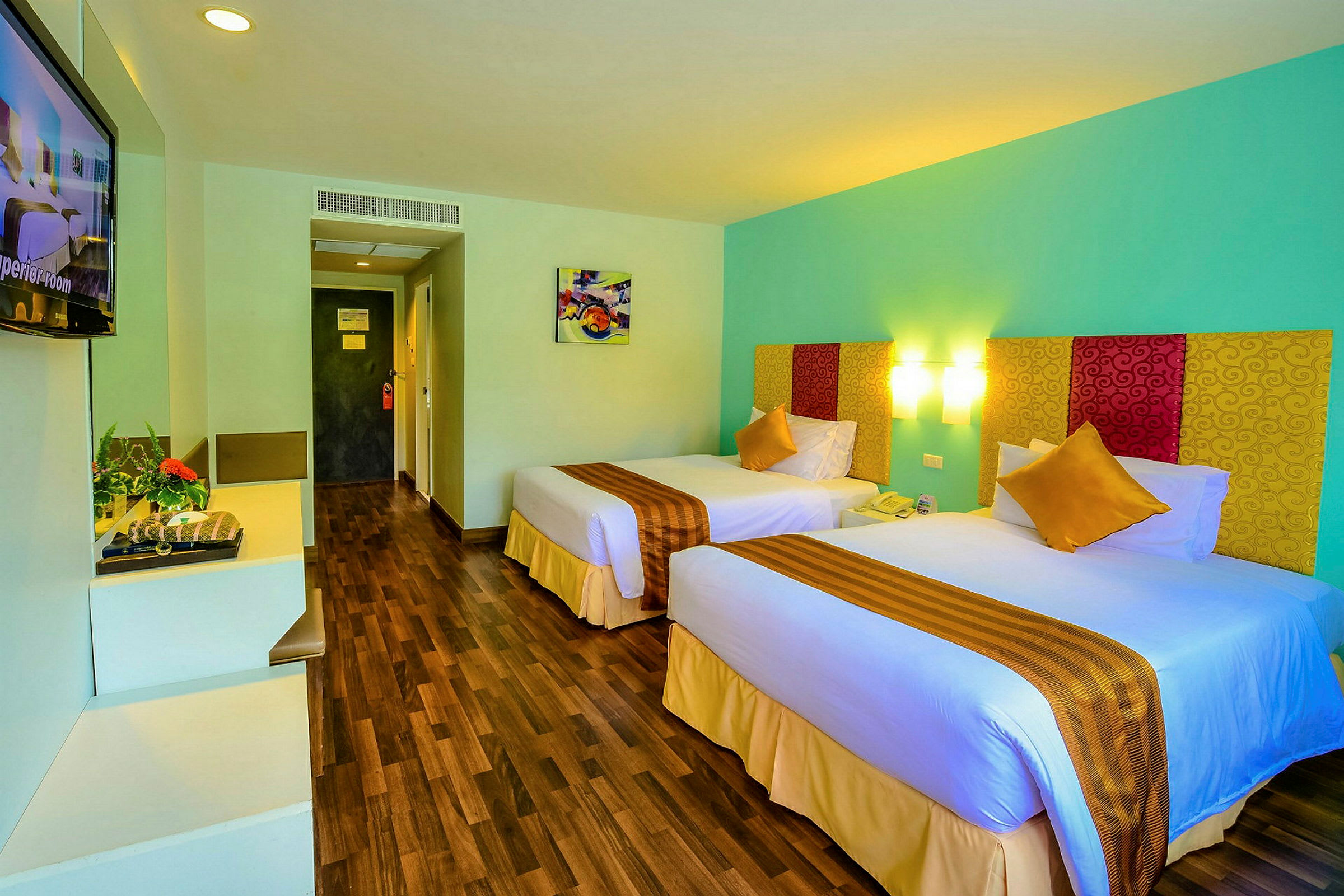 Hotellrum med två enkelsängar, färgglada överkast och väggkonst. (AI-genererad text)