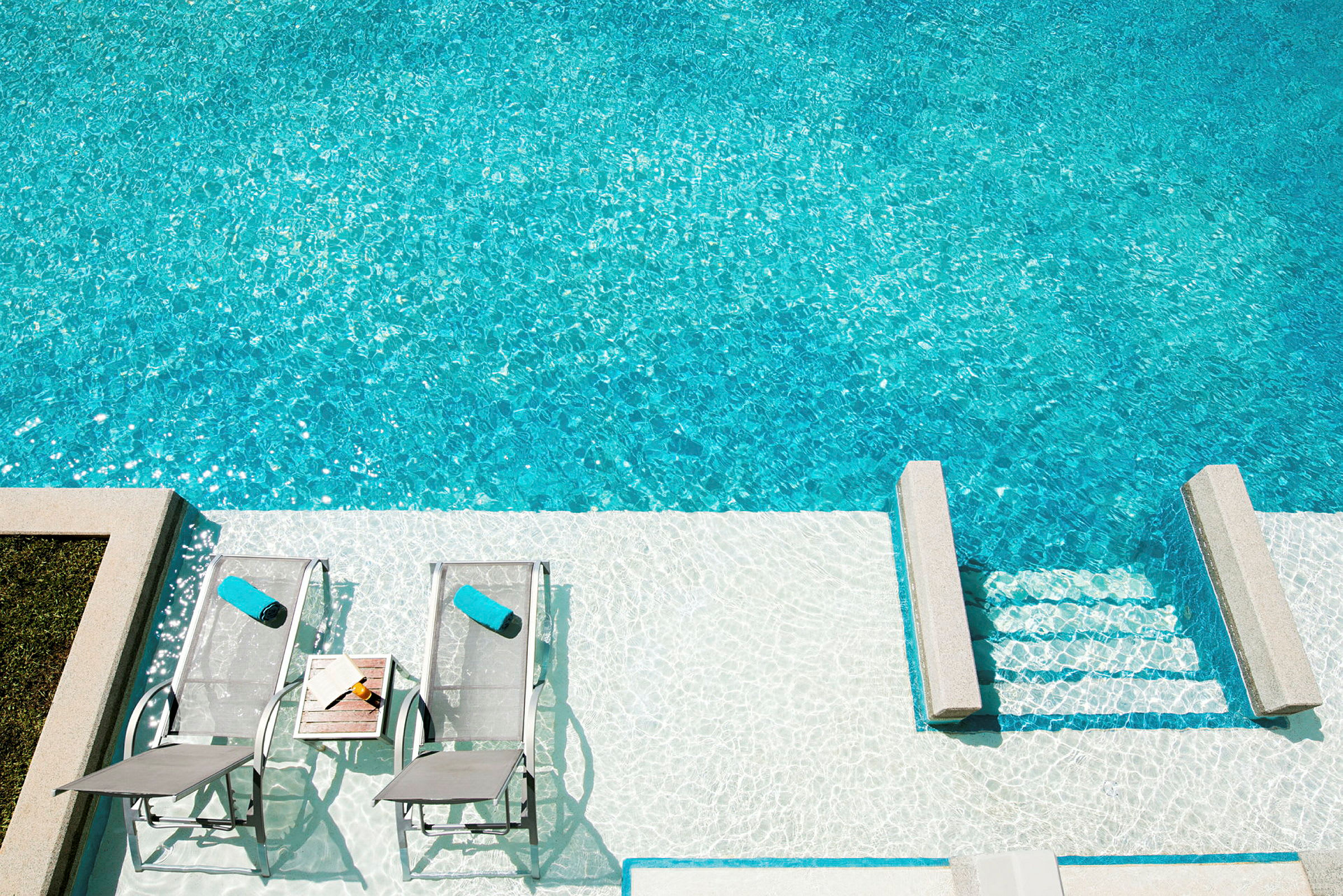 Solsängar med handdukar bredvid en pool. (AI-genererad text)