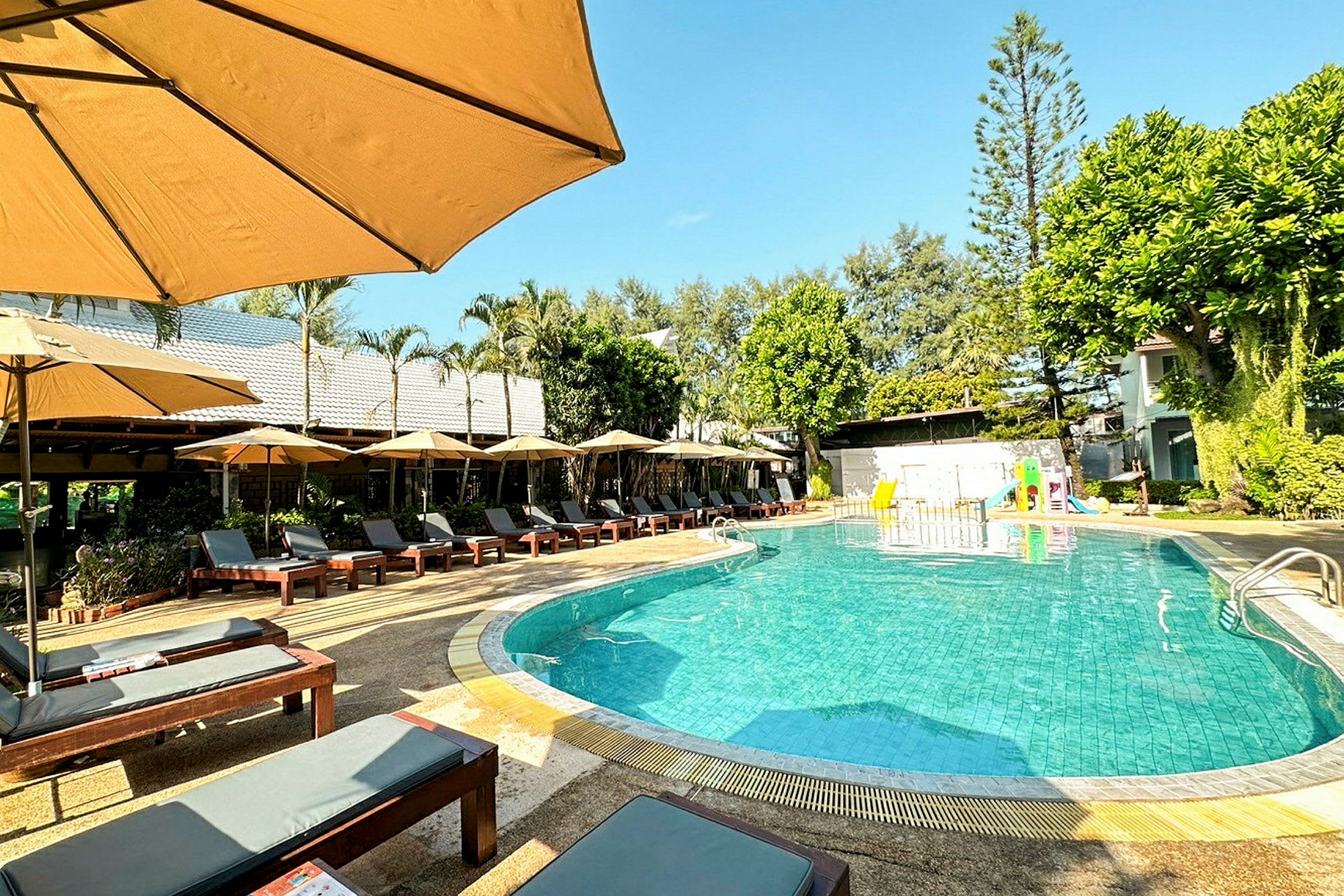 Utomhuspool med solstolar och parasoller på hotellområde. (AI-genererad text)