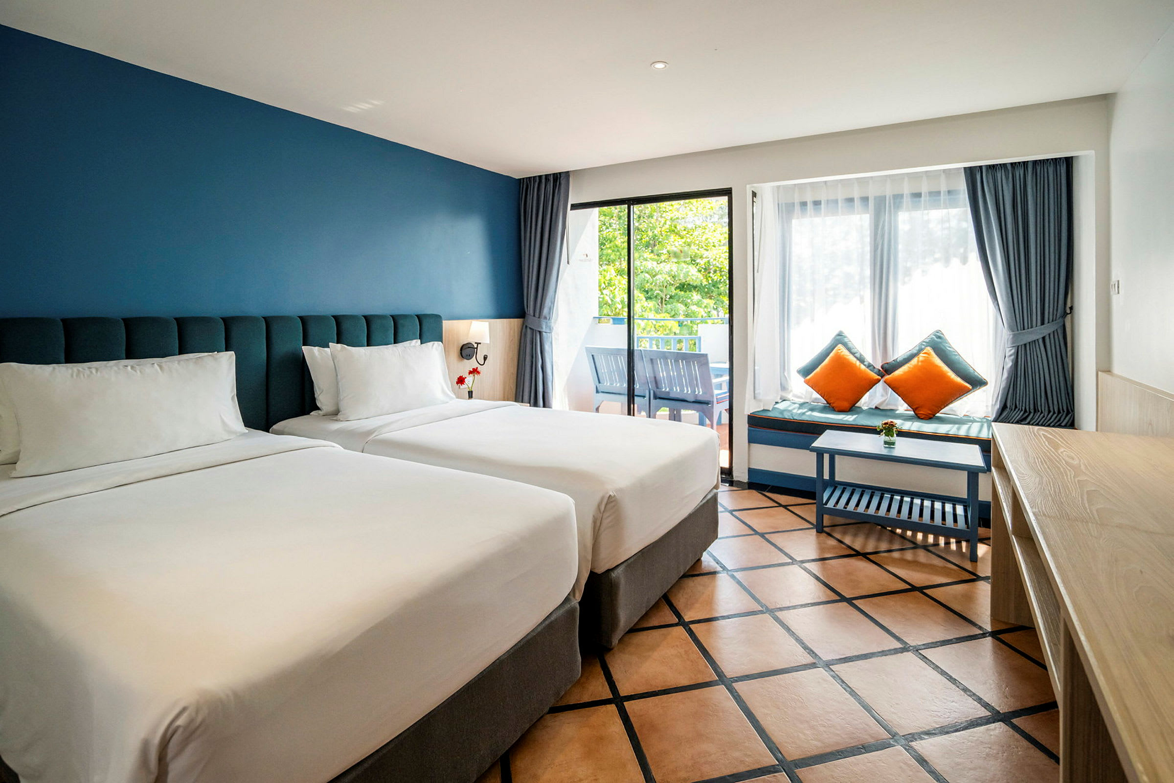 Två enkelsängar i ett hotellrum med blå väggar och stora fönster. (AI-genererad text)