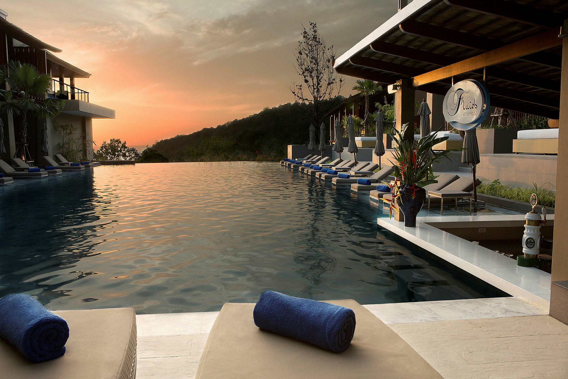 En infinitypool med liggstolar och handdukar på en resort vid solnedgången. (AI-genererad text)