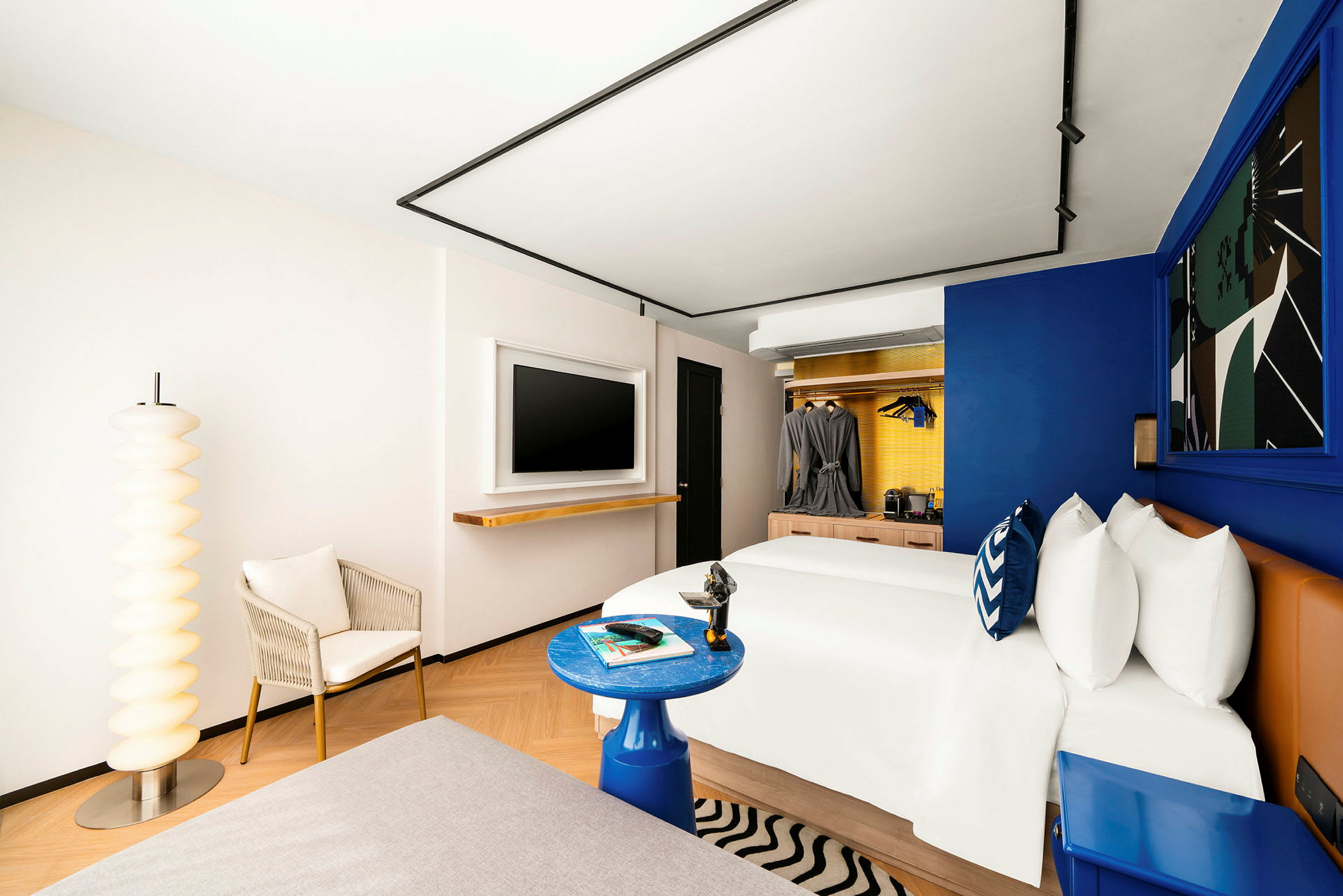 Ett modernt hotellrum med en stor säng, dekorativ inredning och en fåtölj vid sidan av en unik golvlampa. (AI-genererad text)