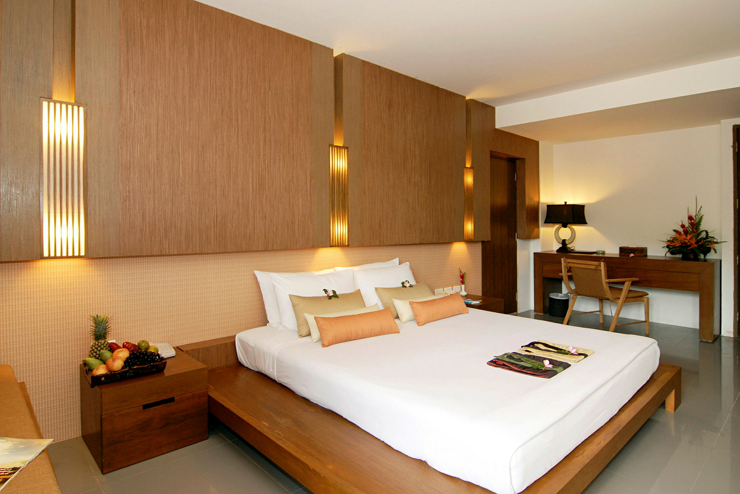 Hotellrum med en stor säng, träinredning och ett skrivbord med stol. (AI-genererad text)