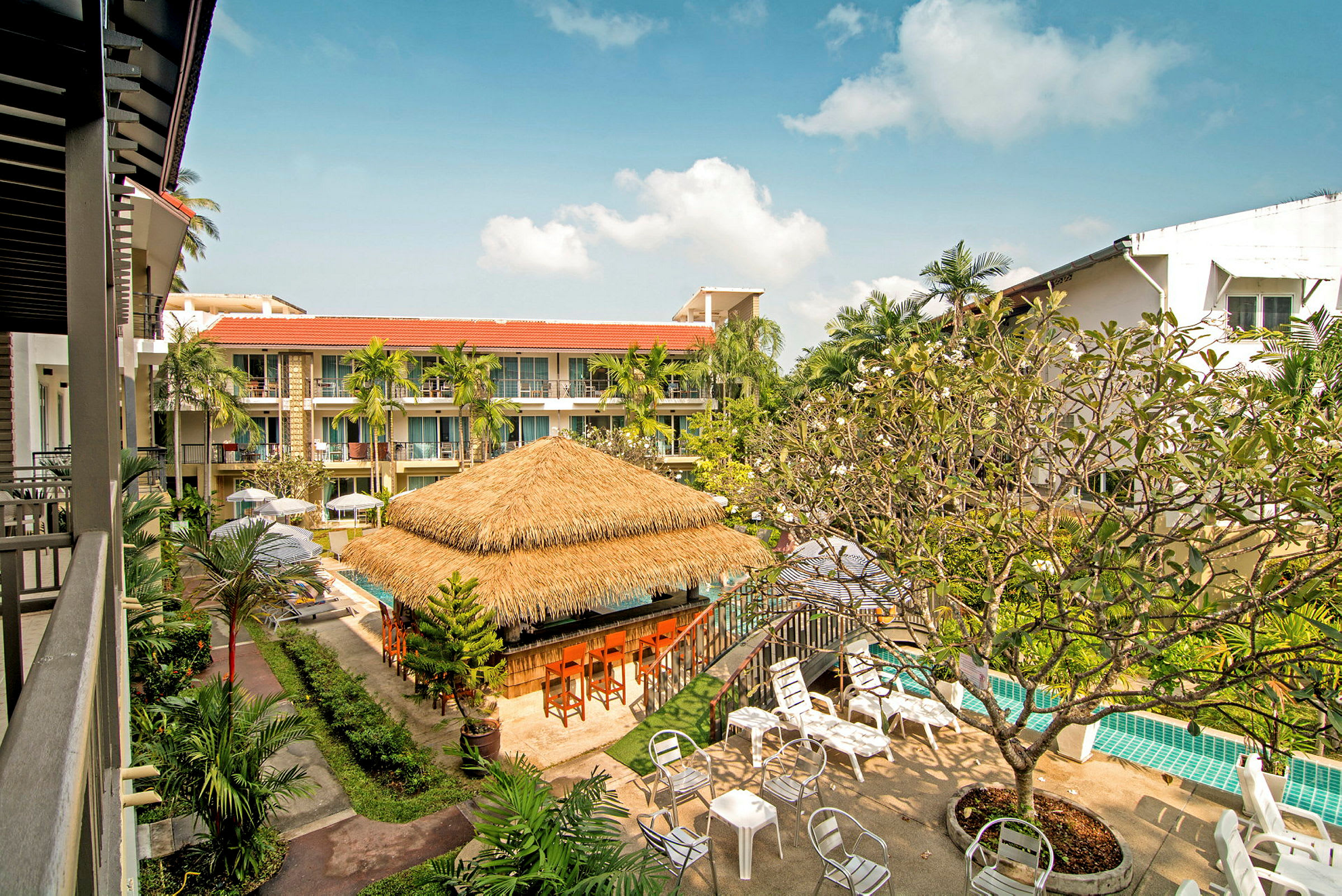 Hotellbyggnad med poolområde, parasoll, och trädgård. (AI-genererad text)