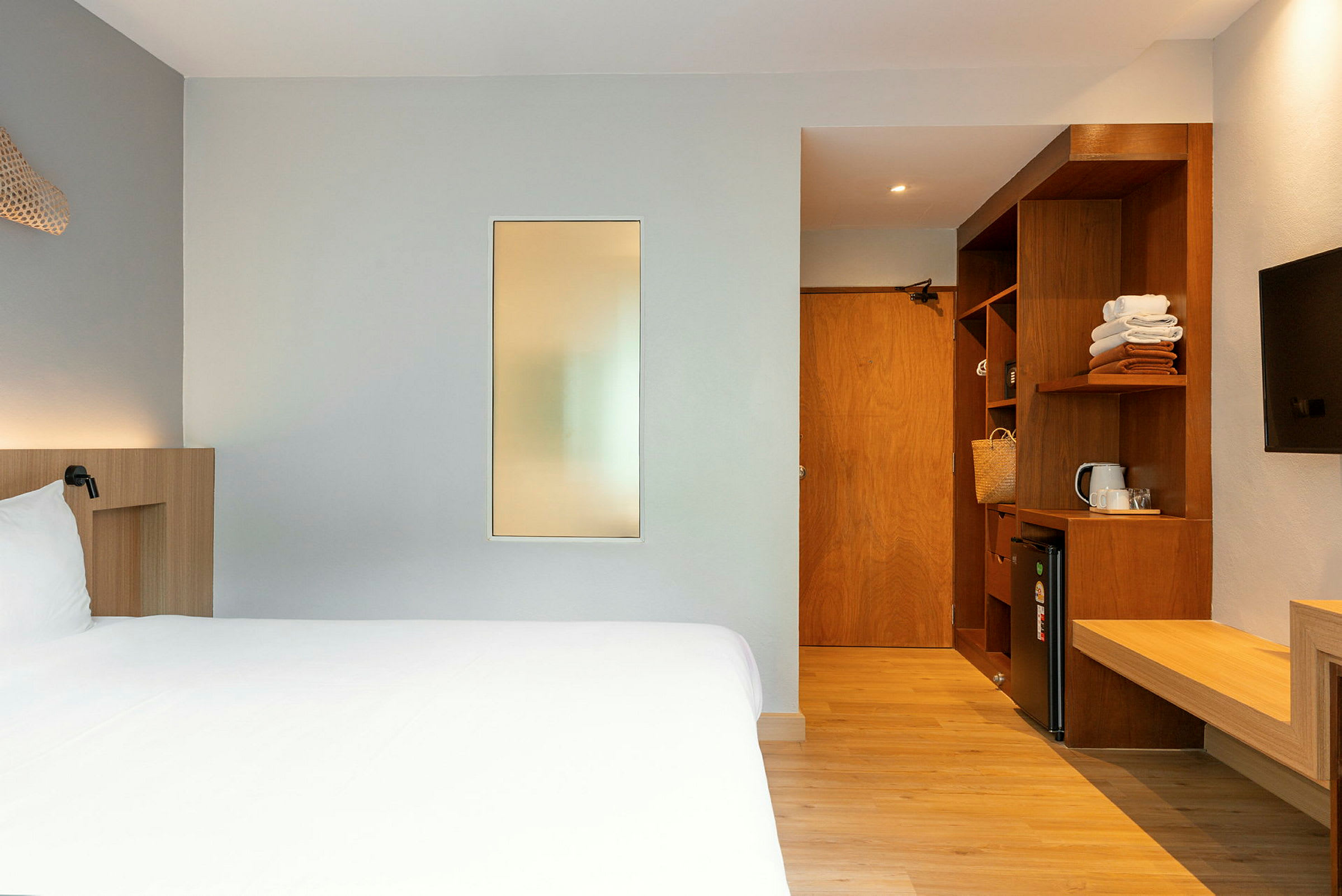 Ett hotellrum med en säng, en garderob, en minibar och en tv. (AI-genererad text)